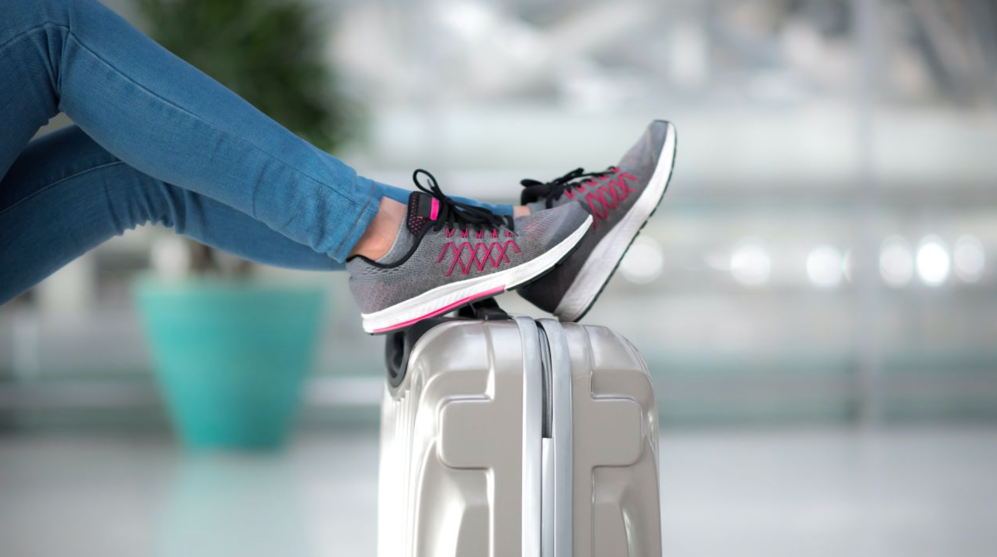 A woman's legs with sneakers on her feet propped up on a suitcase