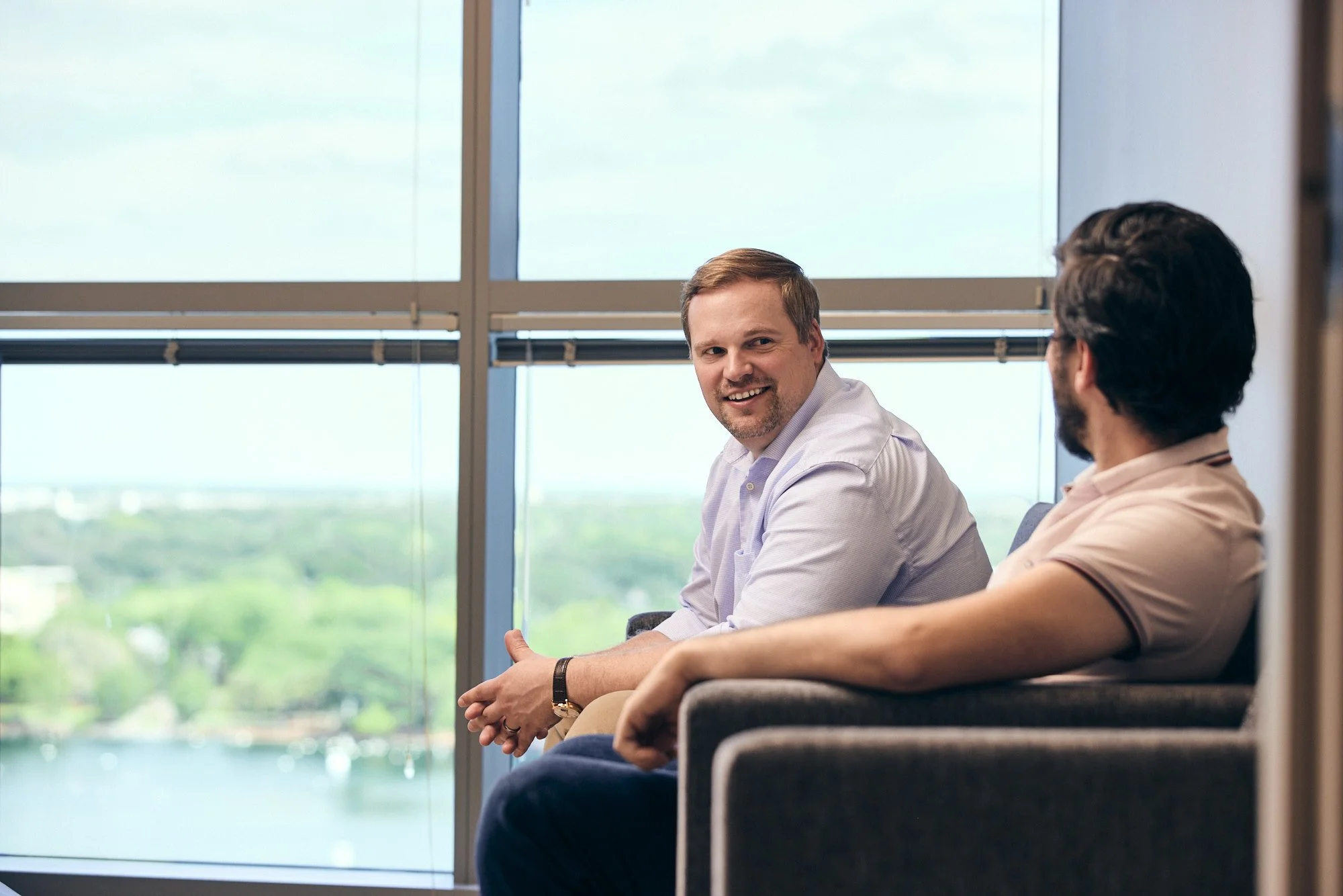 photograph of two men talking on breakroom couch