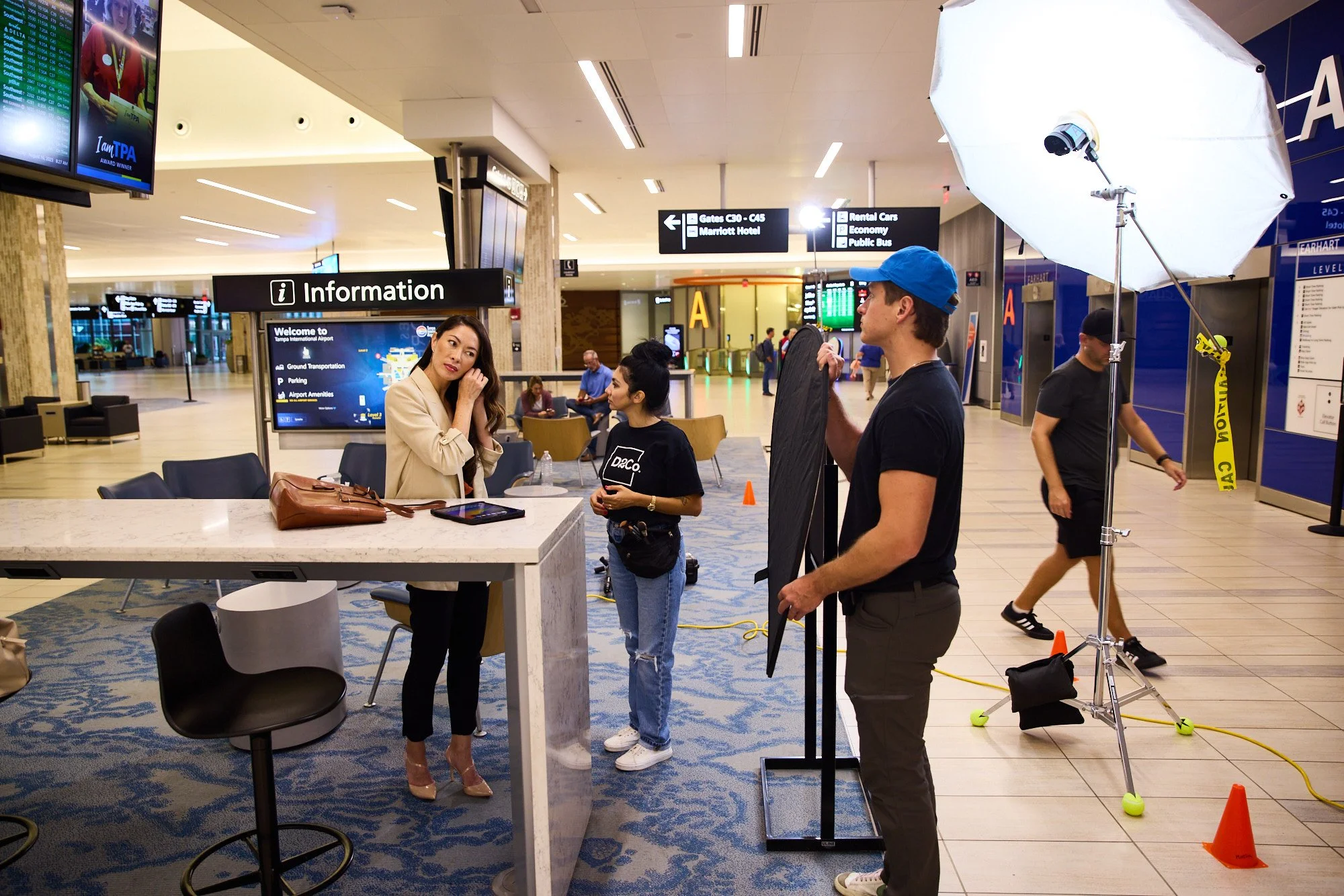 Behind the scenes photo shoot, crew and talent with a softbox setup in an airport terminal