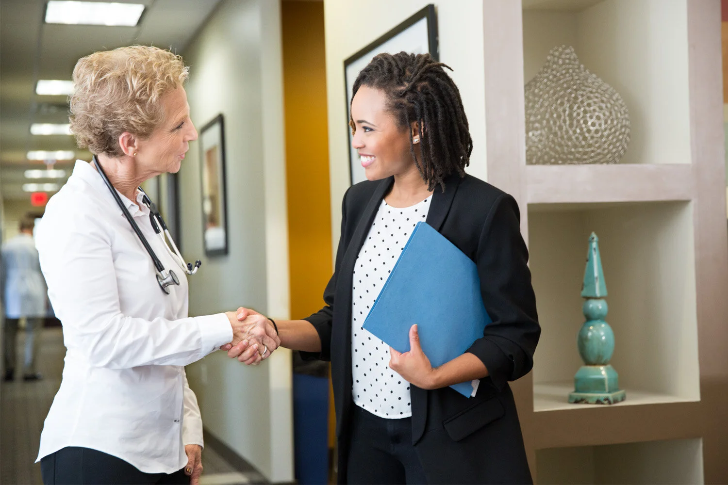 Photograph of females shaking hands in doctors office