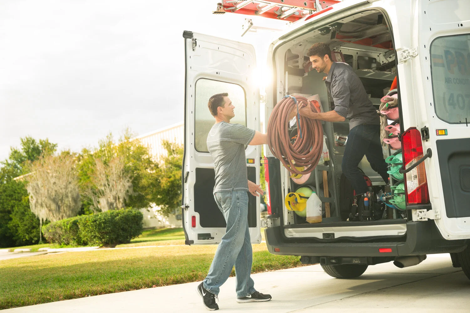 Photograph of two men unloading work van
