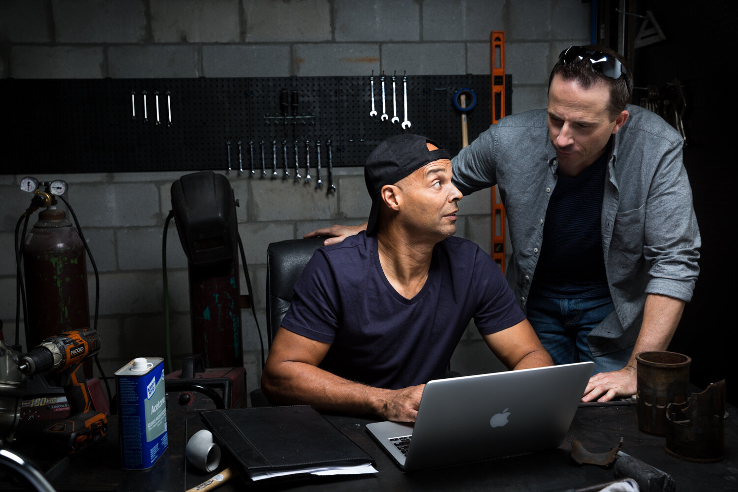 Photograph of men at garage looking over computer