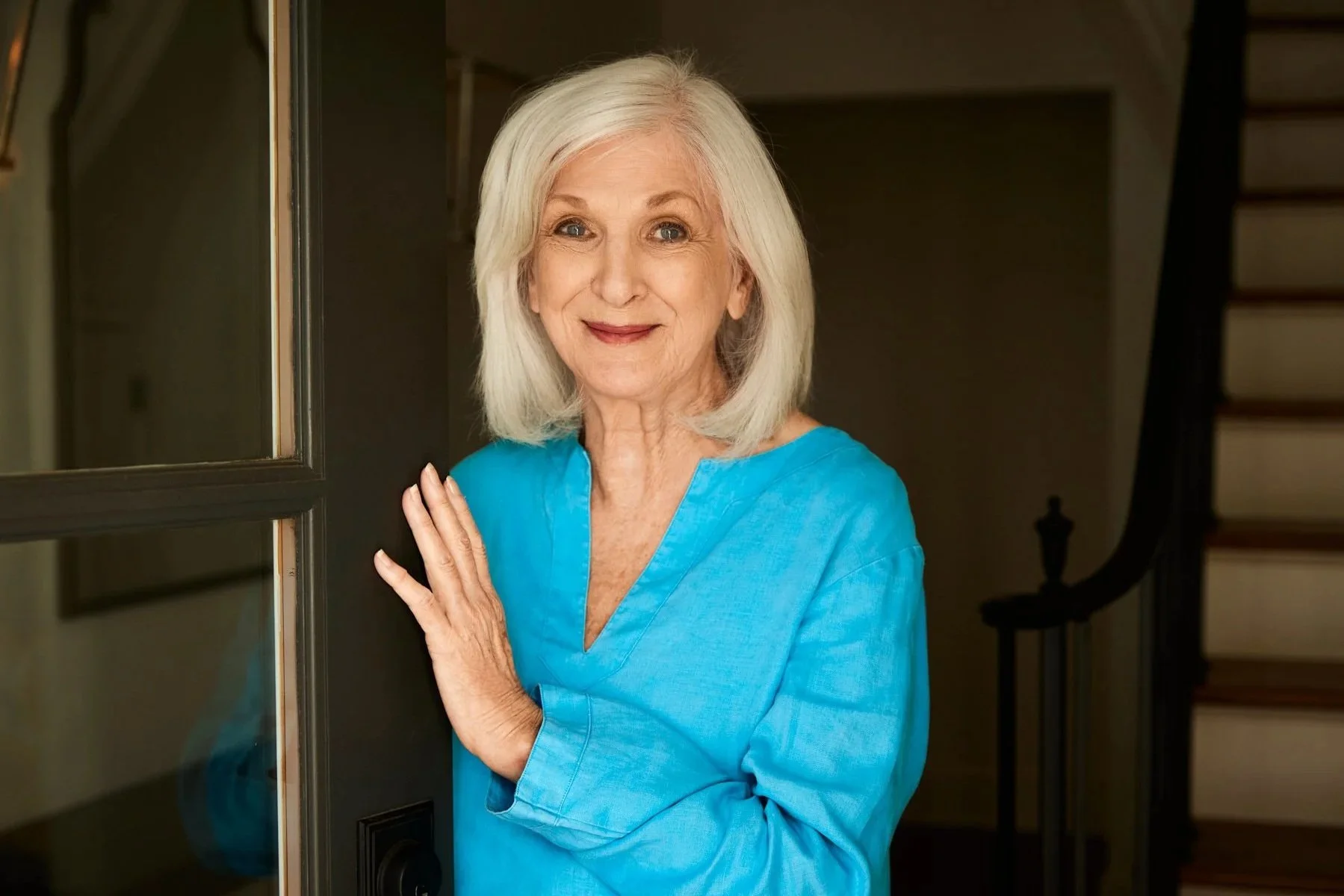 photo of retired female smiling slightly at the door to welcome guest