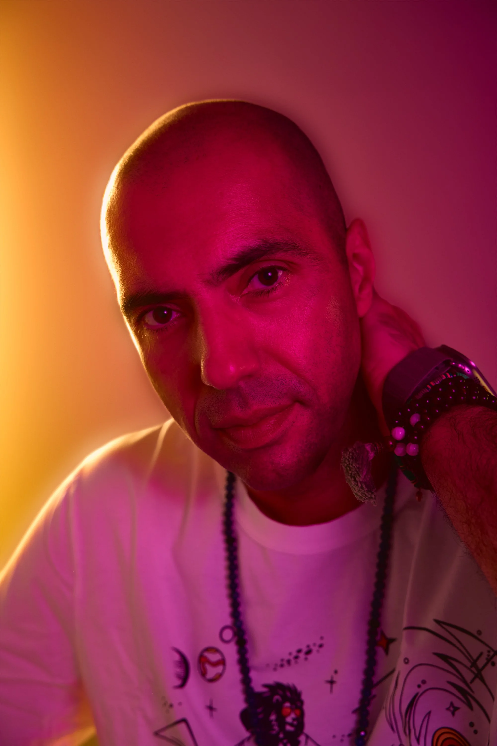 Photo of mans portrait in a studio surrounded by vivid magenta and yellow halo