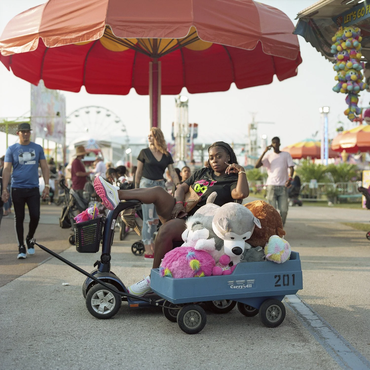 photograph of african american woman with stuffed animals at carnival