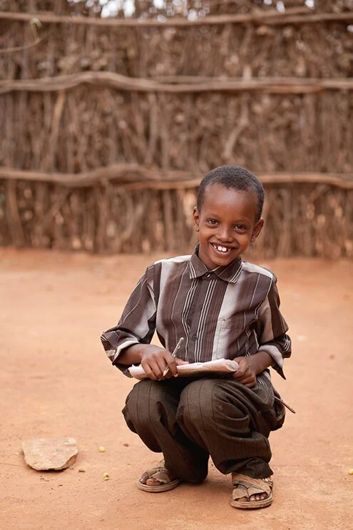 photograph of young boy studying koran and smiling