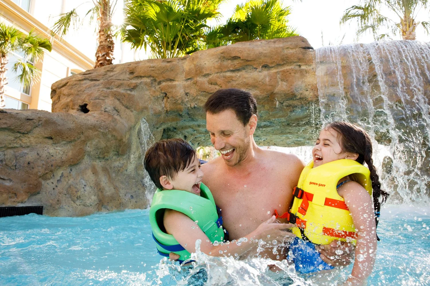 father playing with kids in hotel resort pool