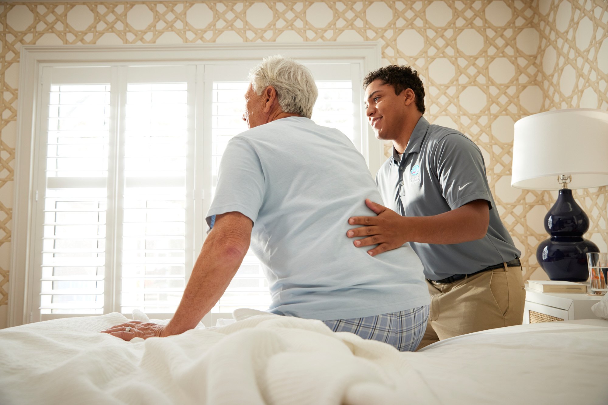 Caregiver assisting an elderly person on a bed