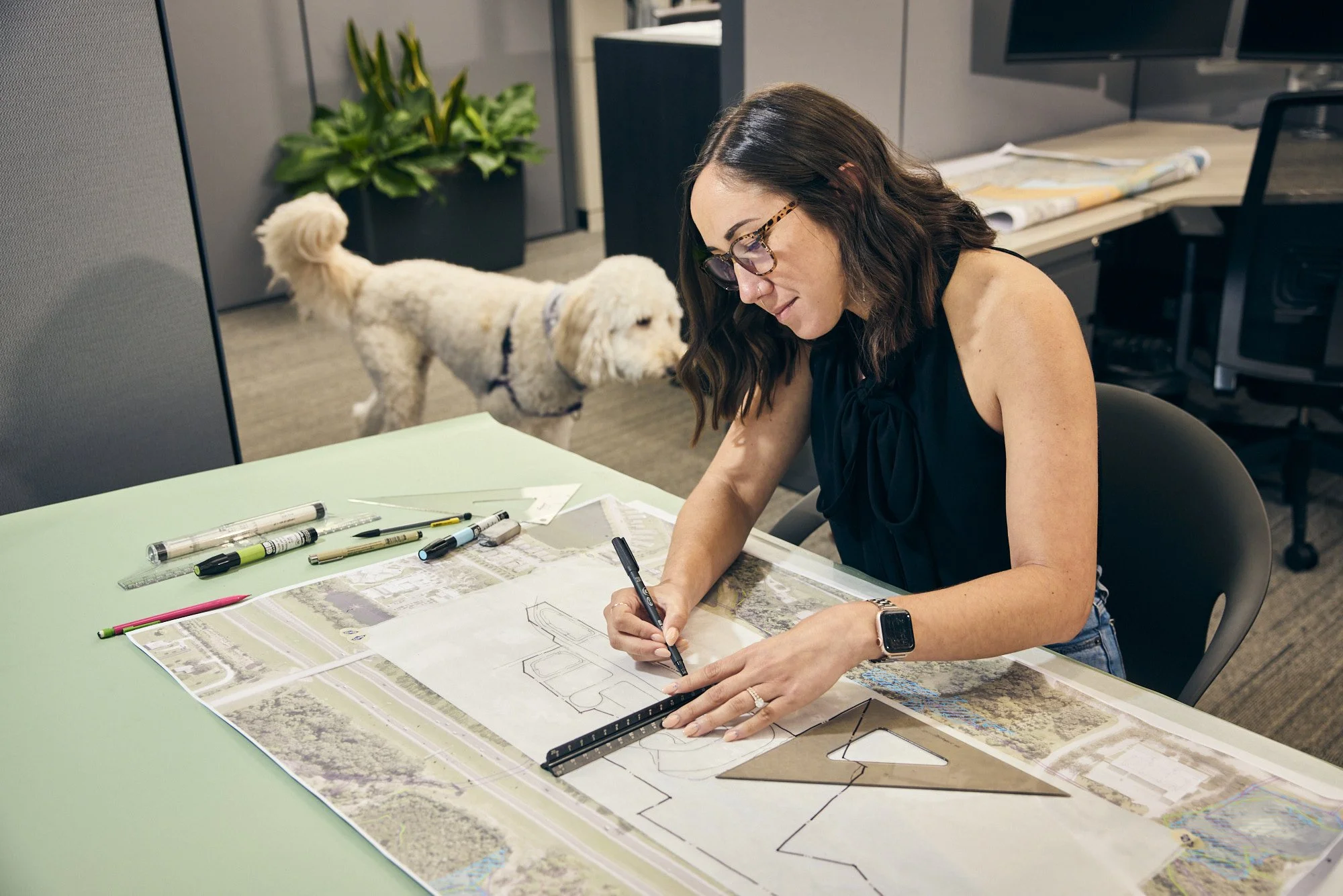 photograph of woman working on architecture plans with dog
