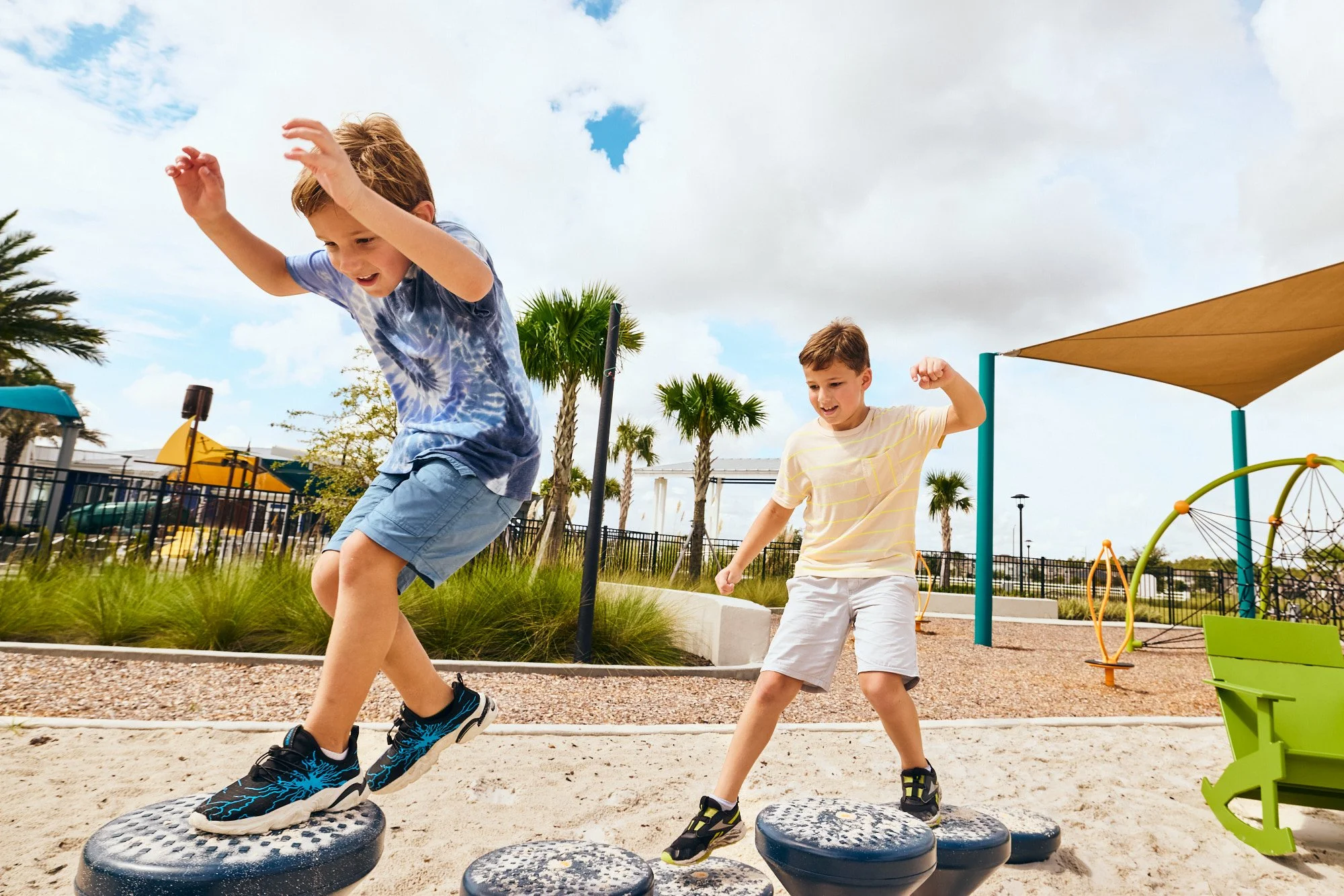 Lifestyle photo of two boys jumping tire steppers at a community playground