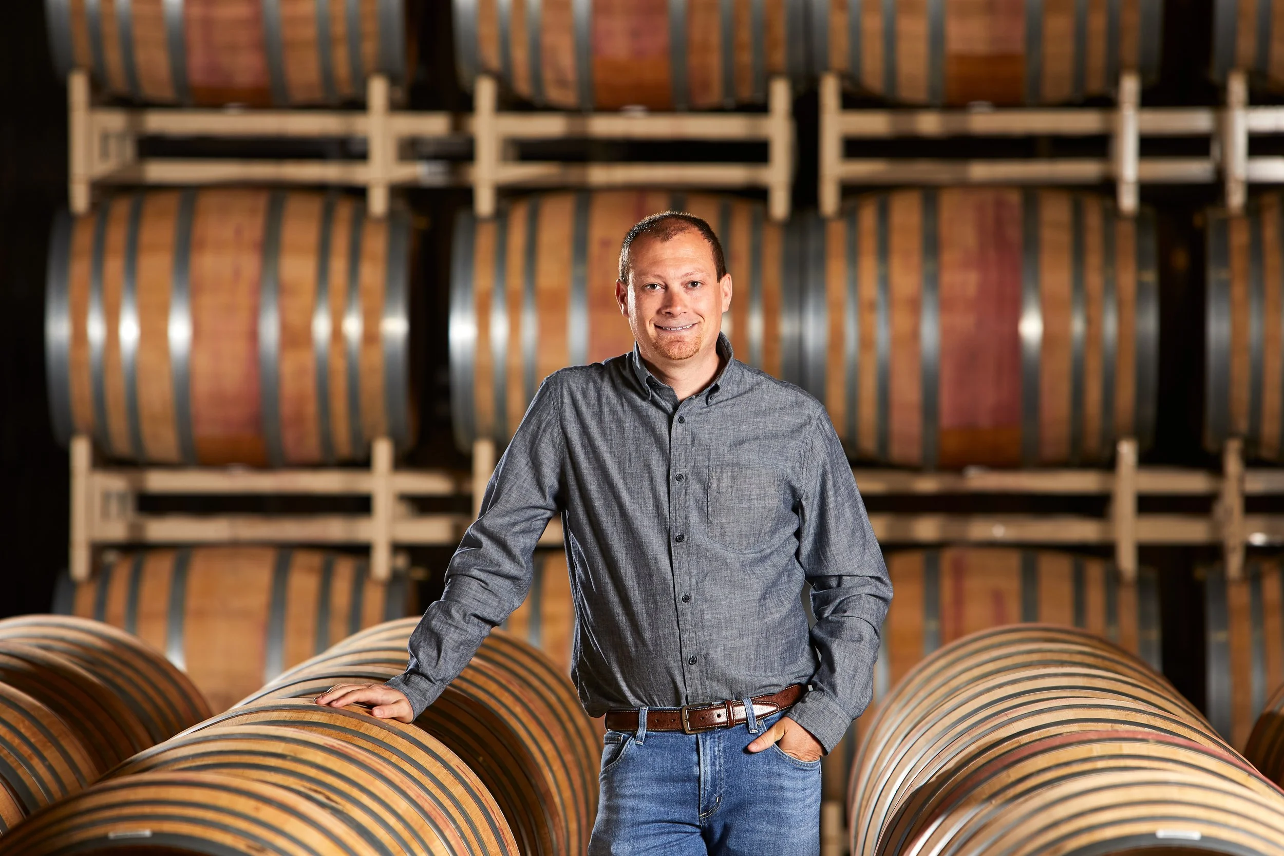 Winemaker and scientist Justin Seidenfeld in wine cellar infront of barrels