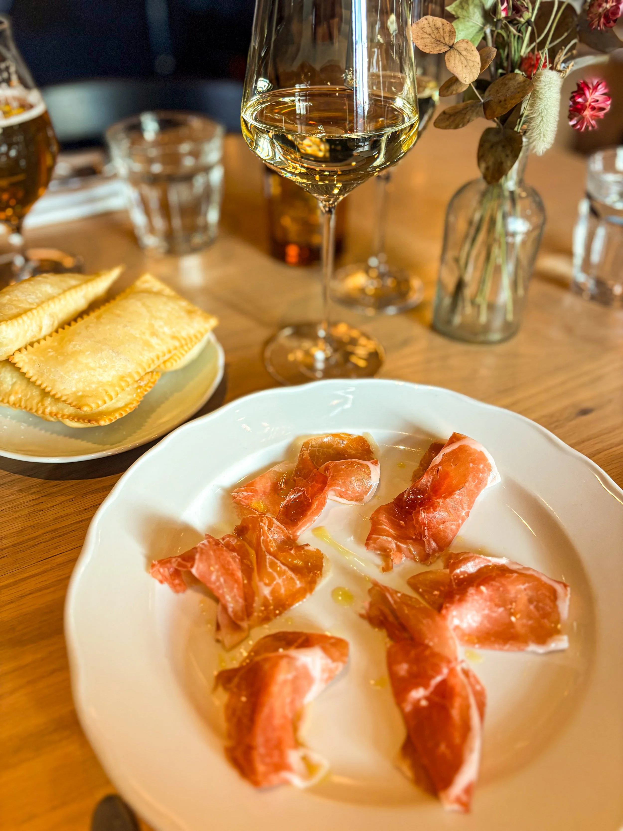 Prosciutto and pastry with a white wine glass