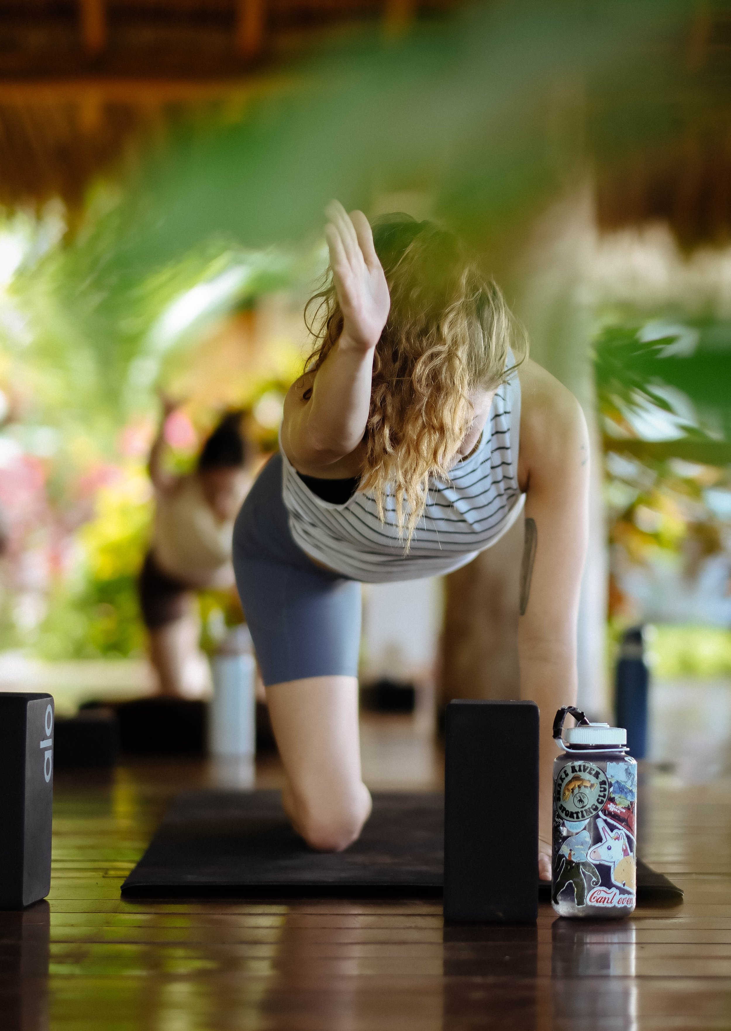 Guest practicing a supported lunge with yoga blocks during a retreat class in the open-air shala in Nicaragua