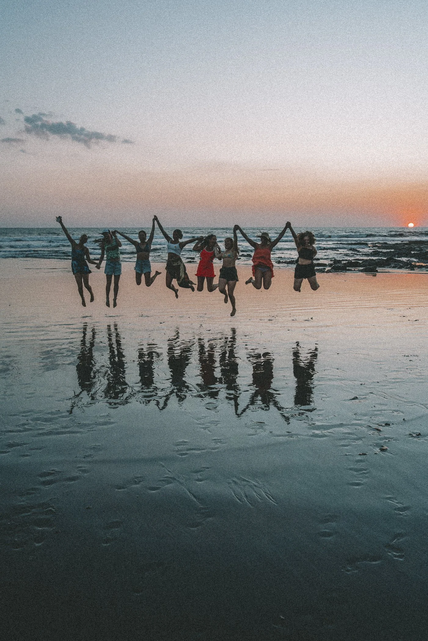 Retreat group holding hands and jumping together at sunset on the beach in Nicaragua