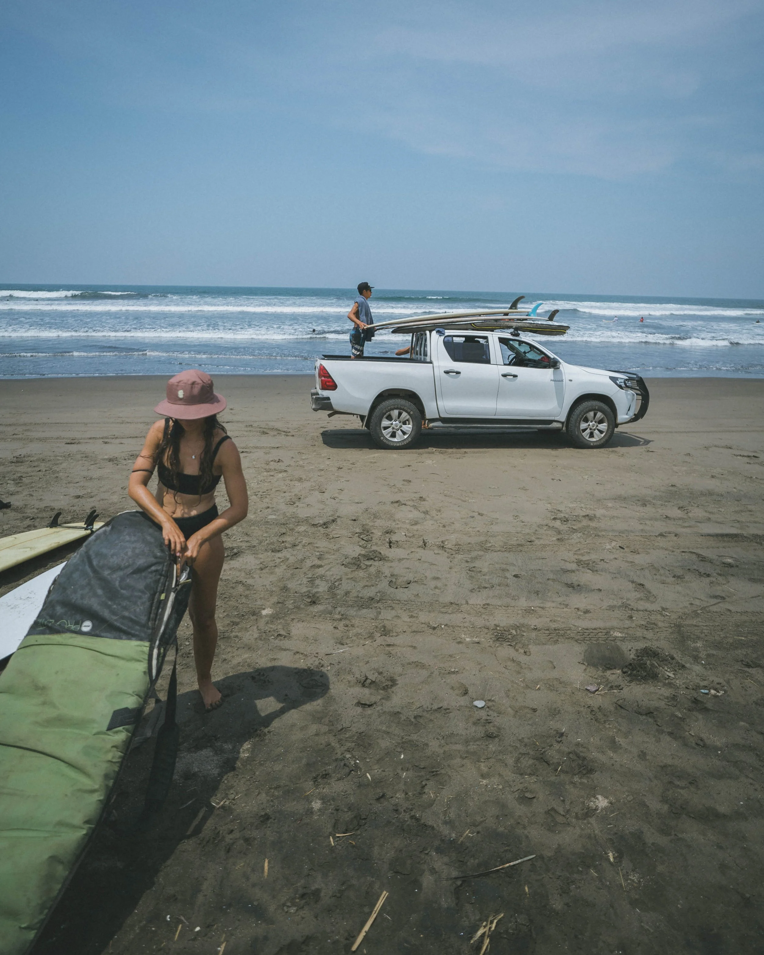 Surf guide truck loaded with boards on an empty beach beside the waves in Northern Nicaragua