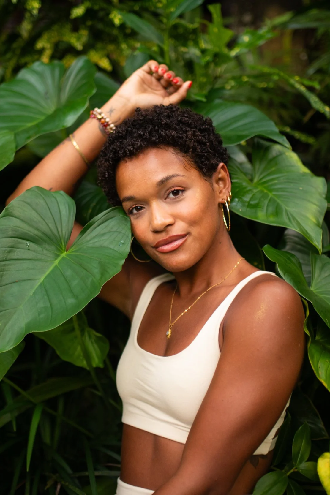 Gabrielle, yoga teacher, smiling among tropical jungle leaves ahead of the EVOLVE yoga teacher immersion in Nicaragua