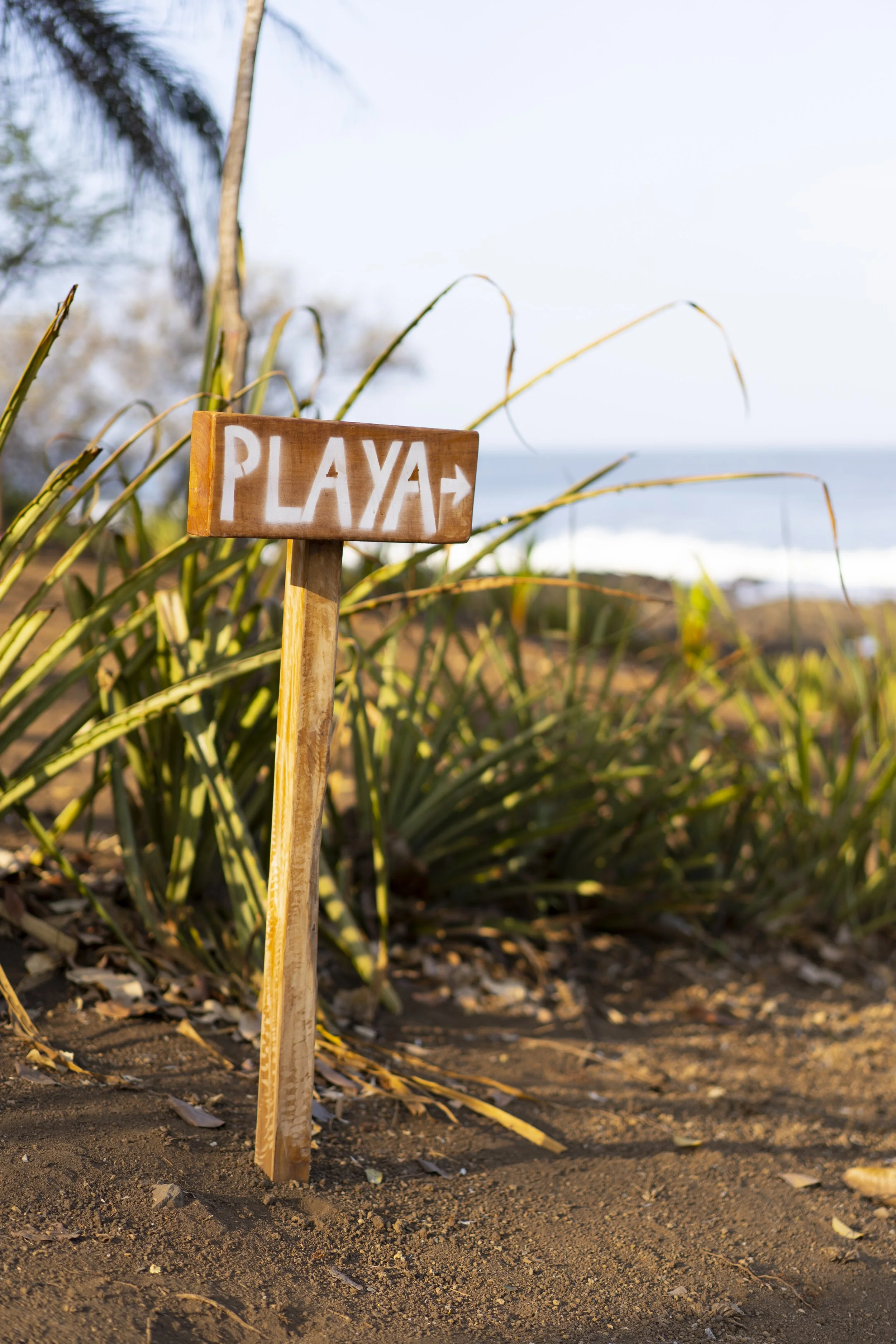 Hand-painted wooden Playa sign pointing toward the beach steps from Still Salty Escape surf and yoga retreat in Nicaragua