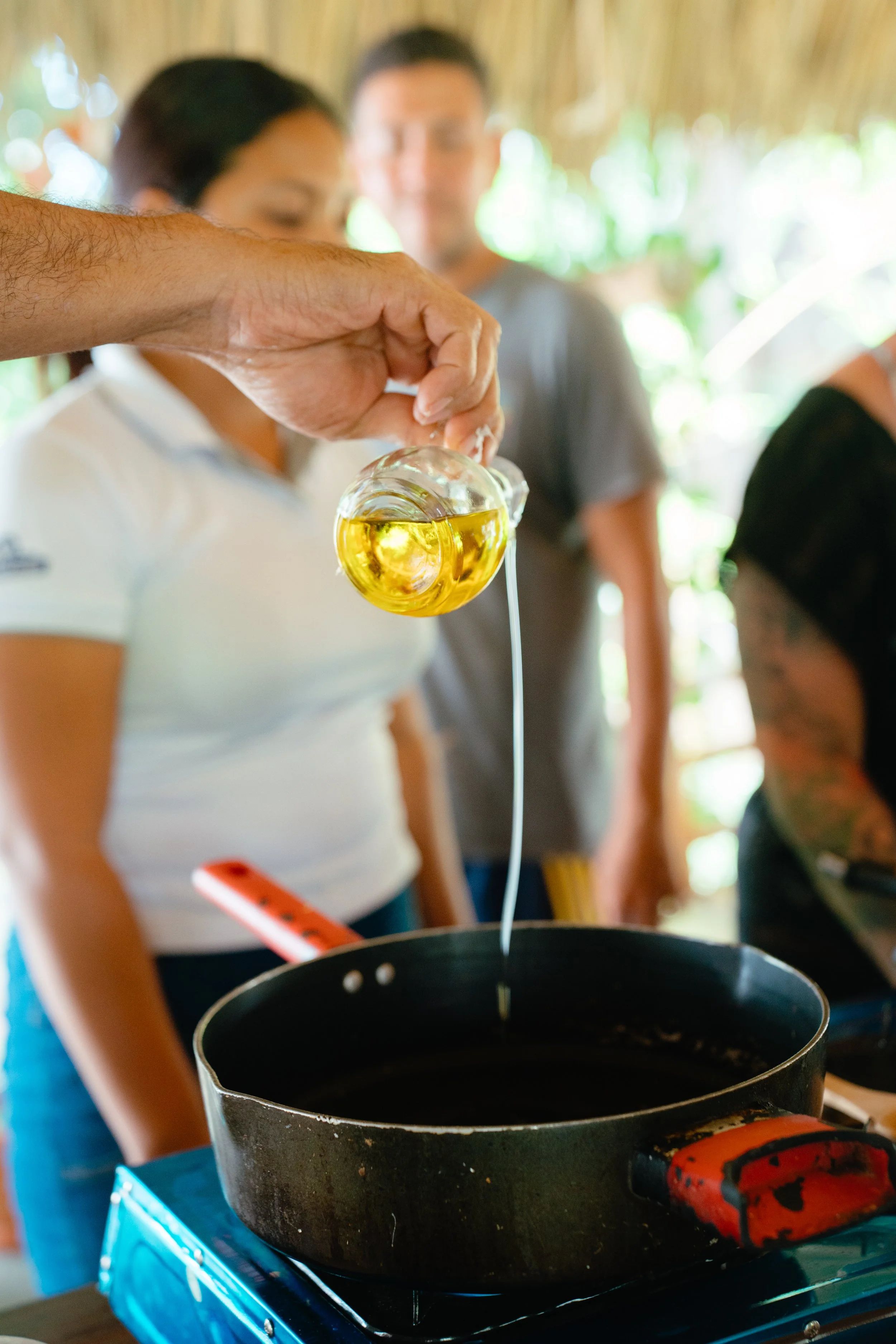 Local cook pouring oil into a pan during a traditional cooking class in Nicaragua