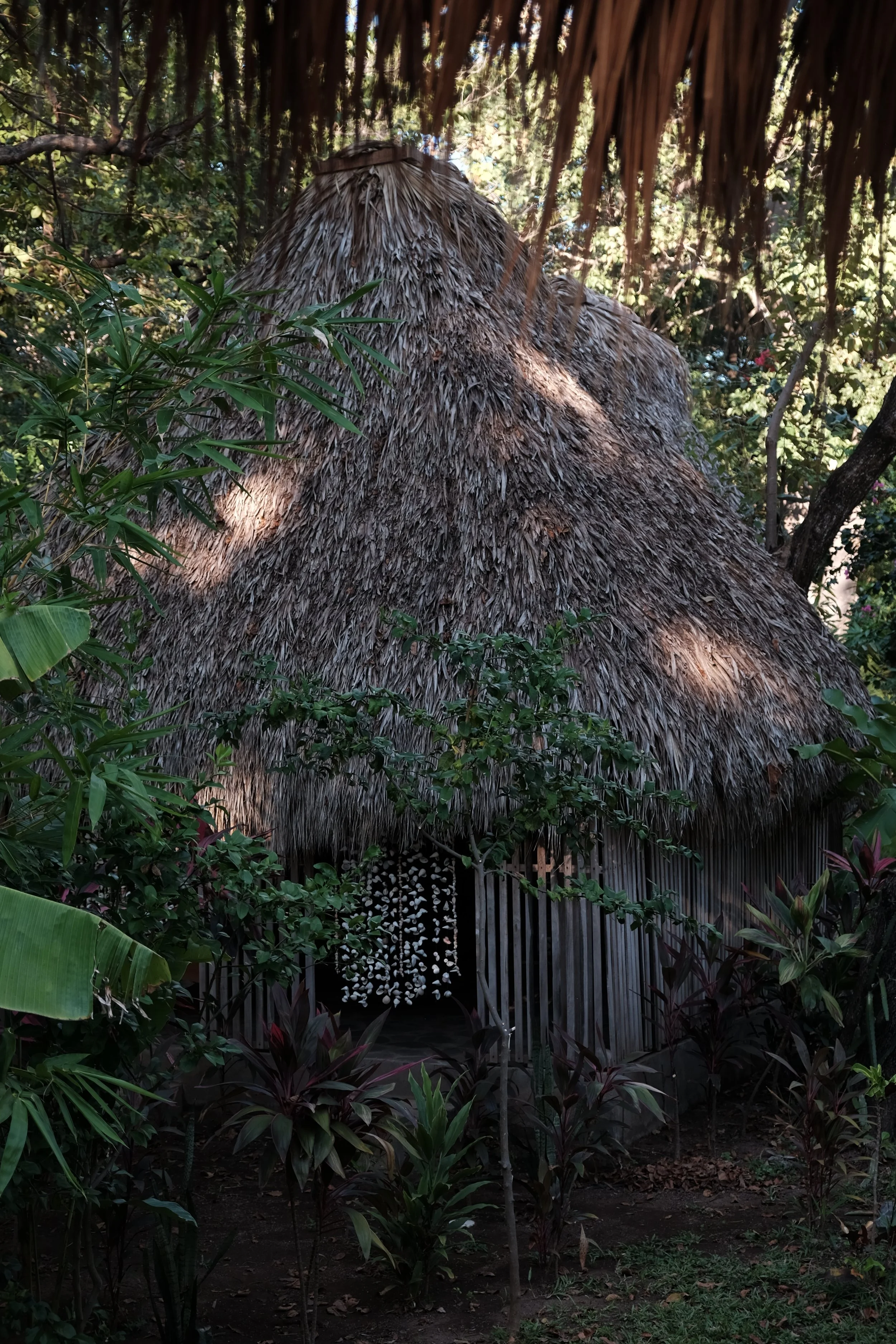 Thatched-roof private massage shala tucked into lush jungle gardens at Still Salty Escape retreat in Nicaragua