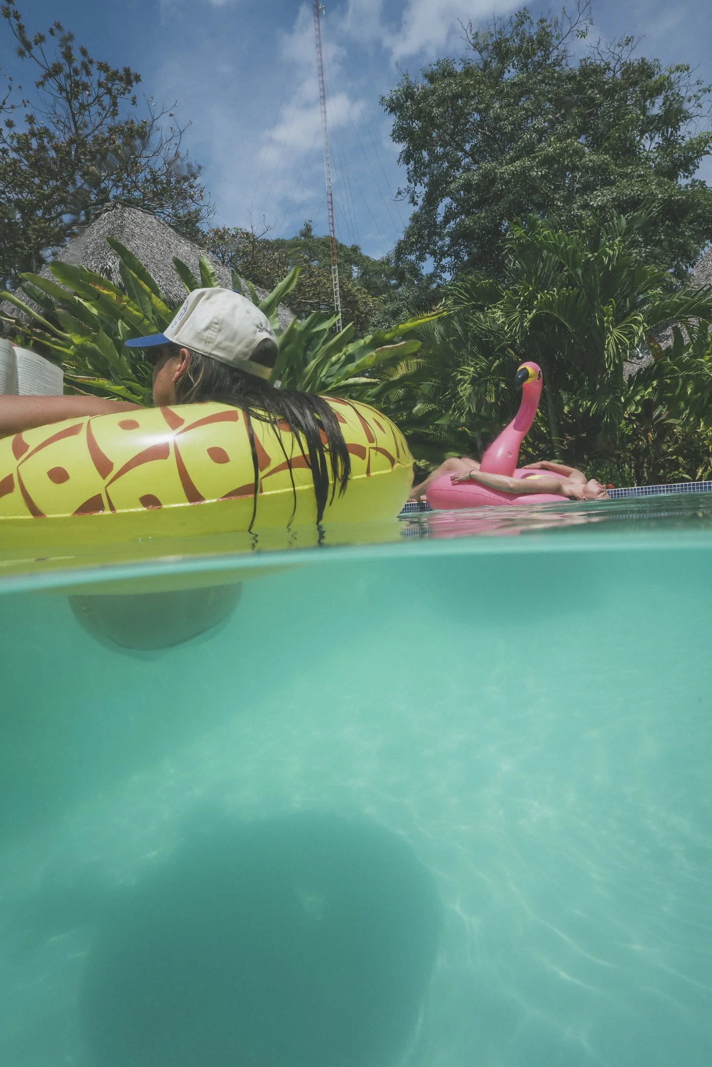 Guests relaxing on pineapple and flamingo floats in the private pool at Still Salty Escape nature hotel in Nicaragua