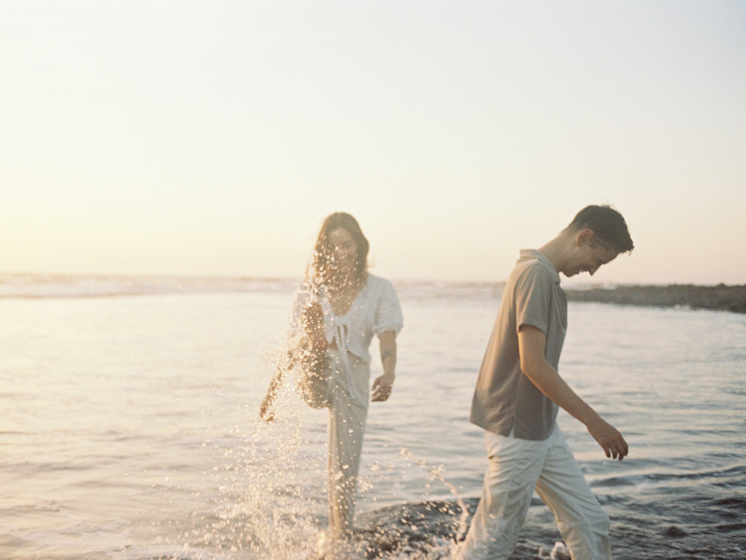 Couple laughing and splashing through the shallows at sunset on a couples retreat in Nicaragua