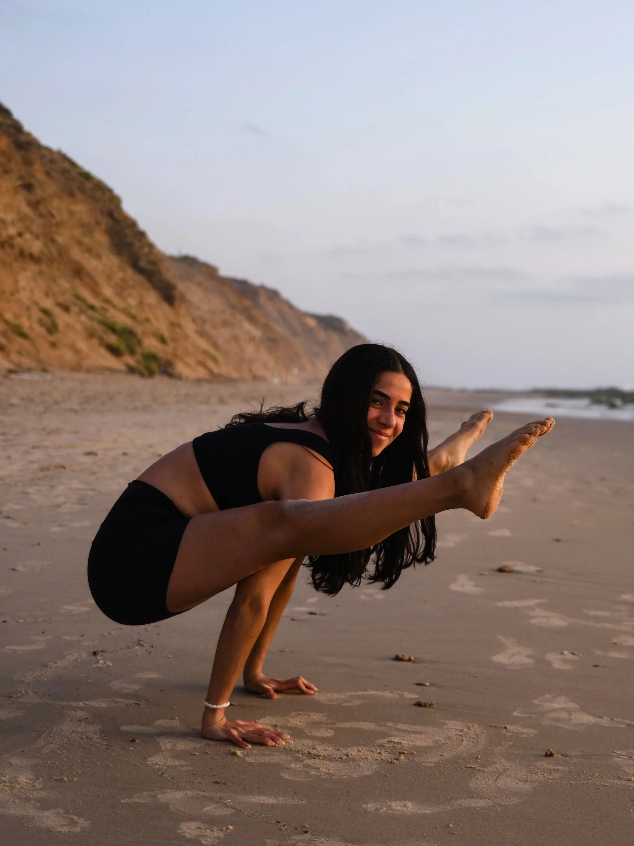 Yoga teacher demonstrating firefly arm balance pose on the beach during a yoga retreat in Nicaragua