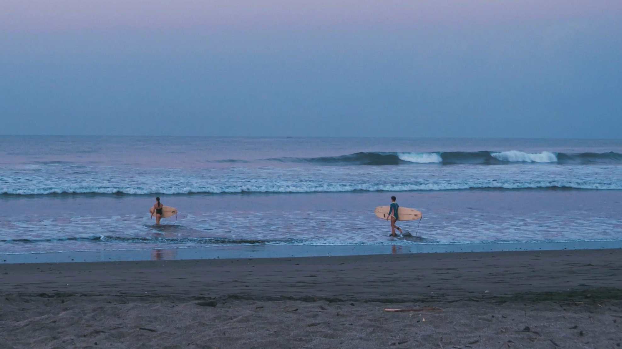 surfer walking into the waves at sunrise at a surf camp in Nicaragua
