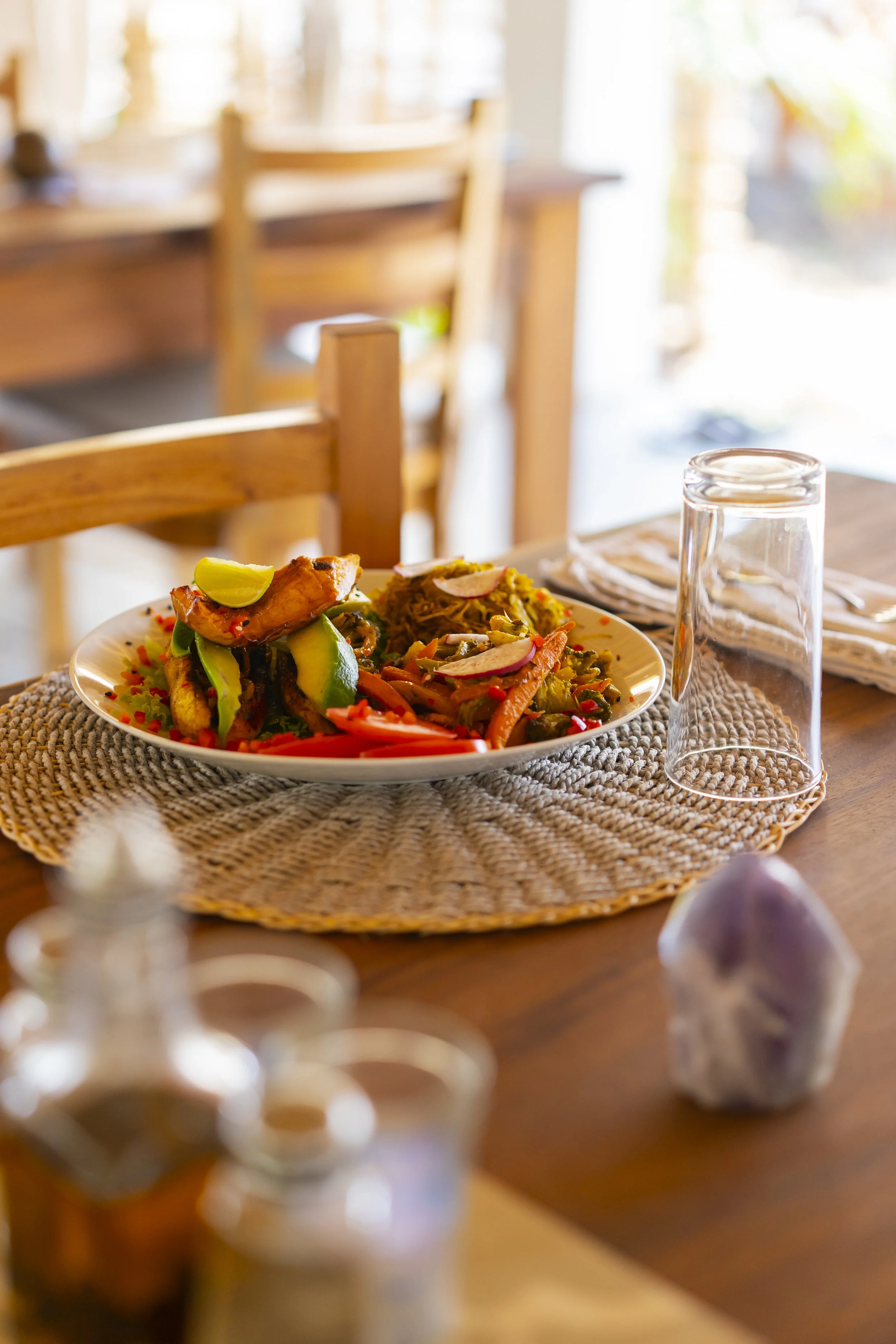 Plated farm-to-table meal on the open-air community dining table with pool and garden views at Still Salty Escape in Nicaragua