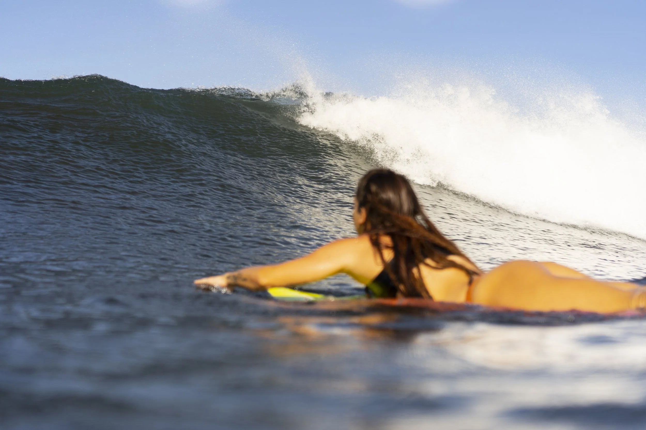 Beginner surfer paddling into a wave during a surf lesson in Nicaragua