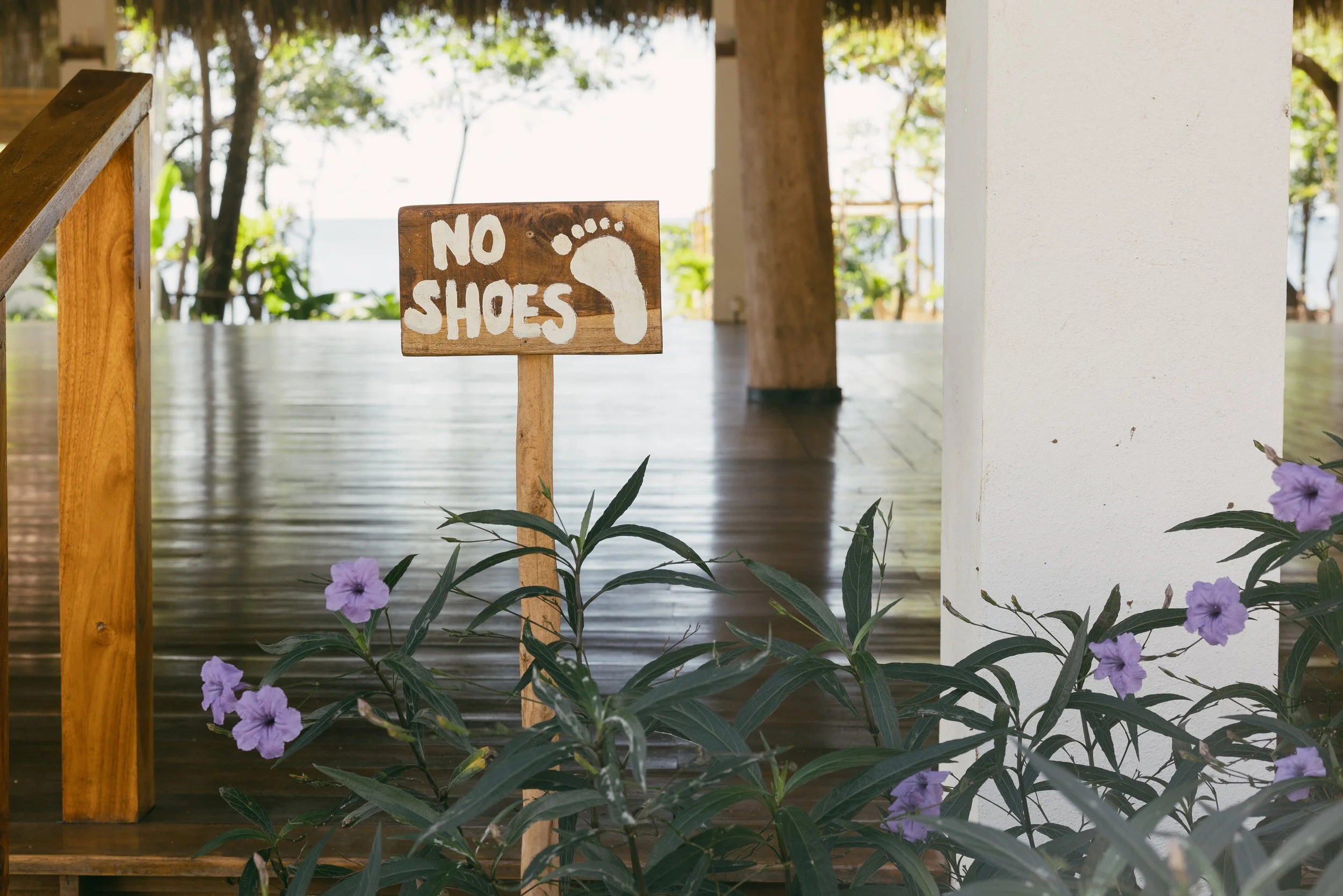Hand-painted no shoes sign at the entrance to the open-air yoga shala deck at a Nicaragua surf and yoga retreat