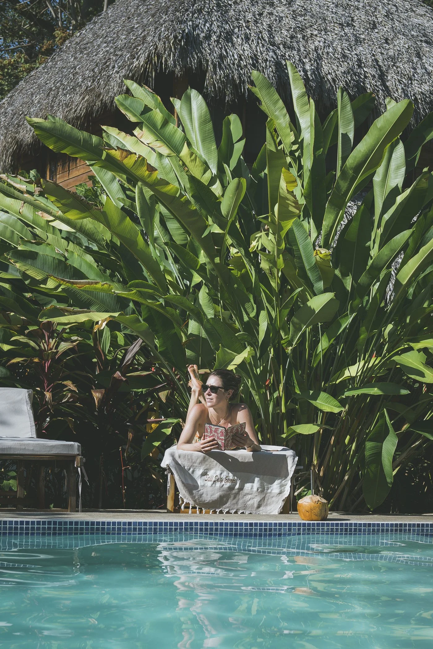 Guest relaxing on a poolside lounge chair after checking in to a surf retreat in Northern Nicaragua
