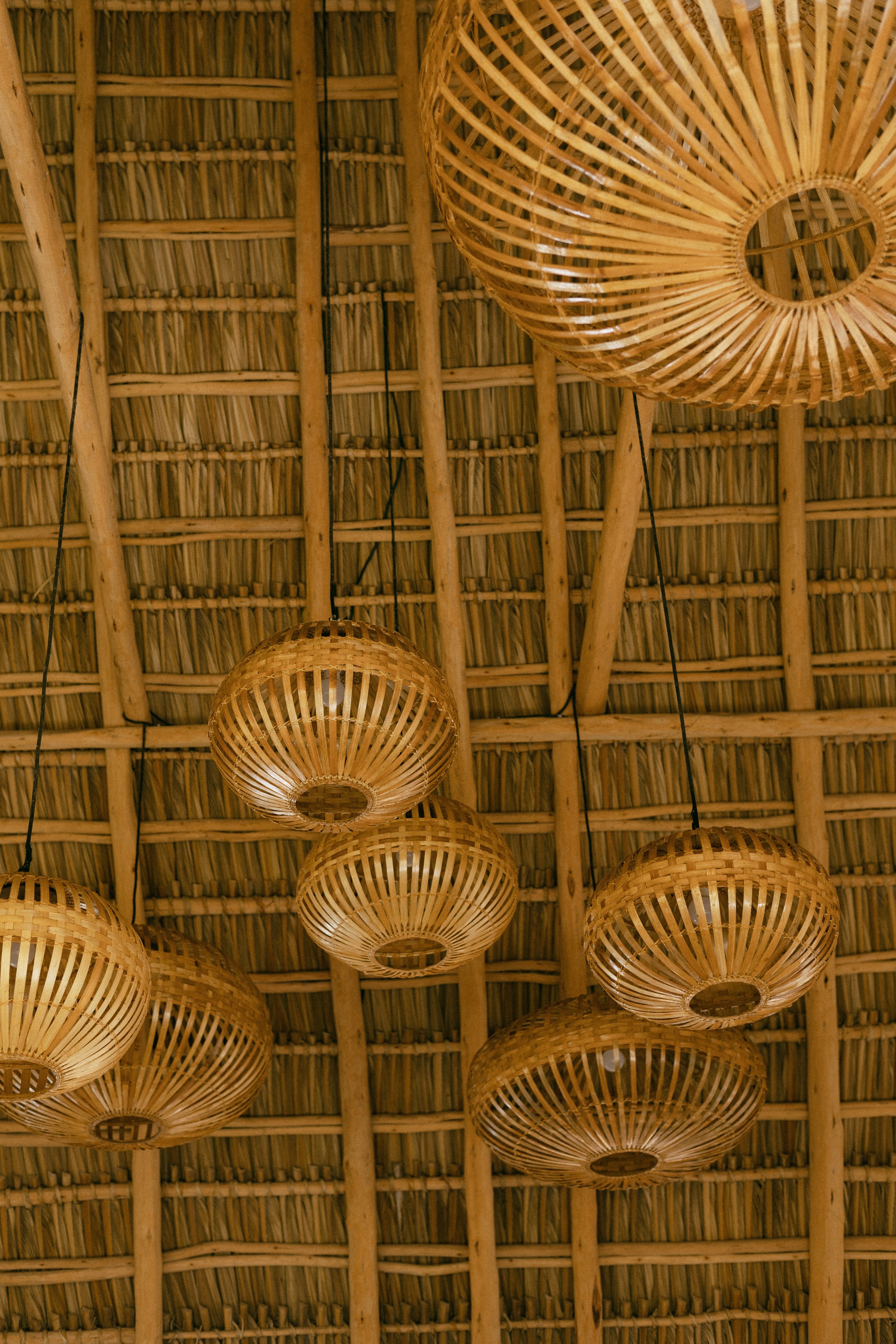 Cluster of handwoven bamboo lanterns beneath a thatched palapa ceiling in the yoga shala at Still Salty Escape Nicaragua
