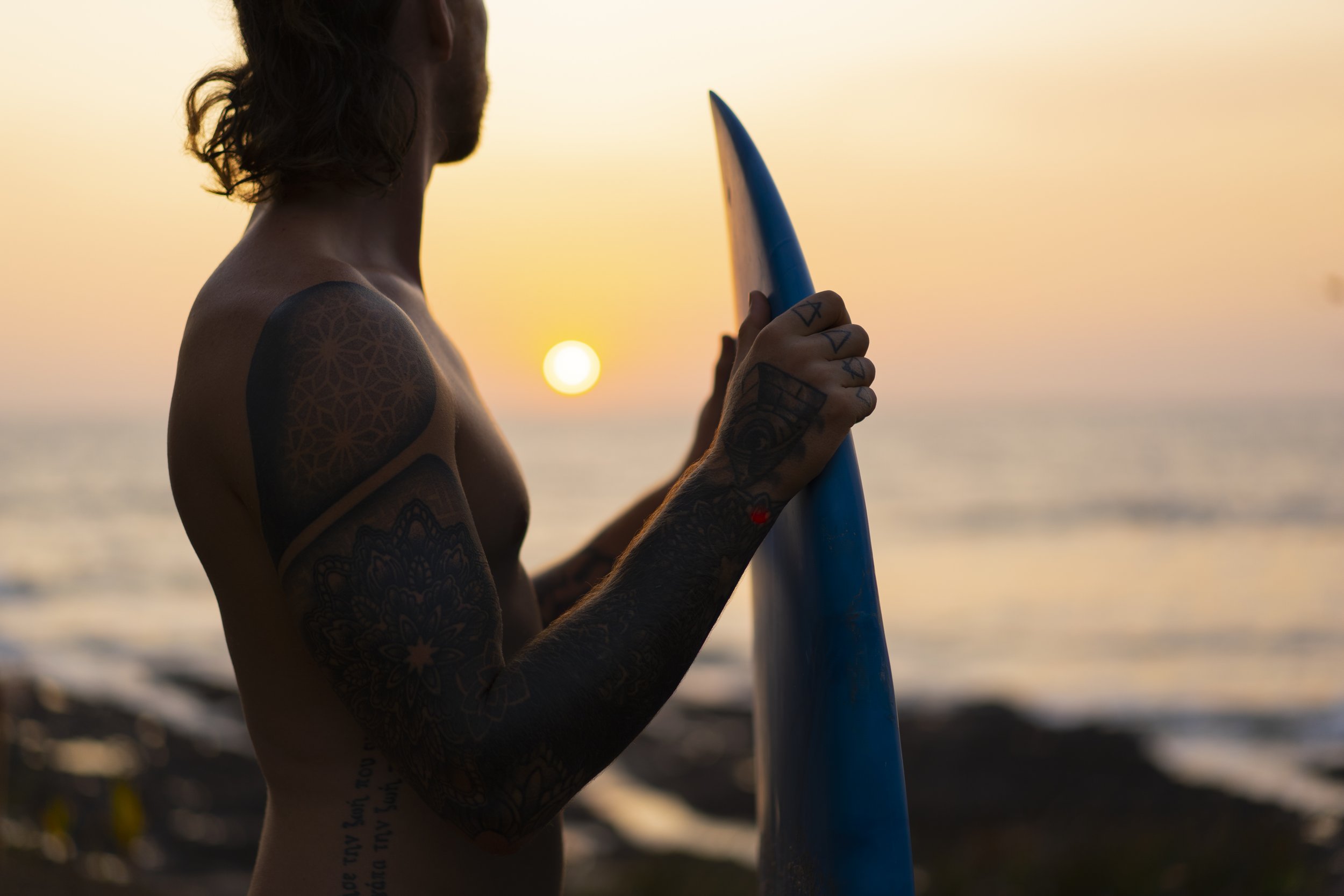 Surfer standing on the beach holding a board at sunset, looking out at uncrowded waves at Still Salty Escape in Nicaragua