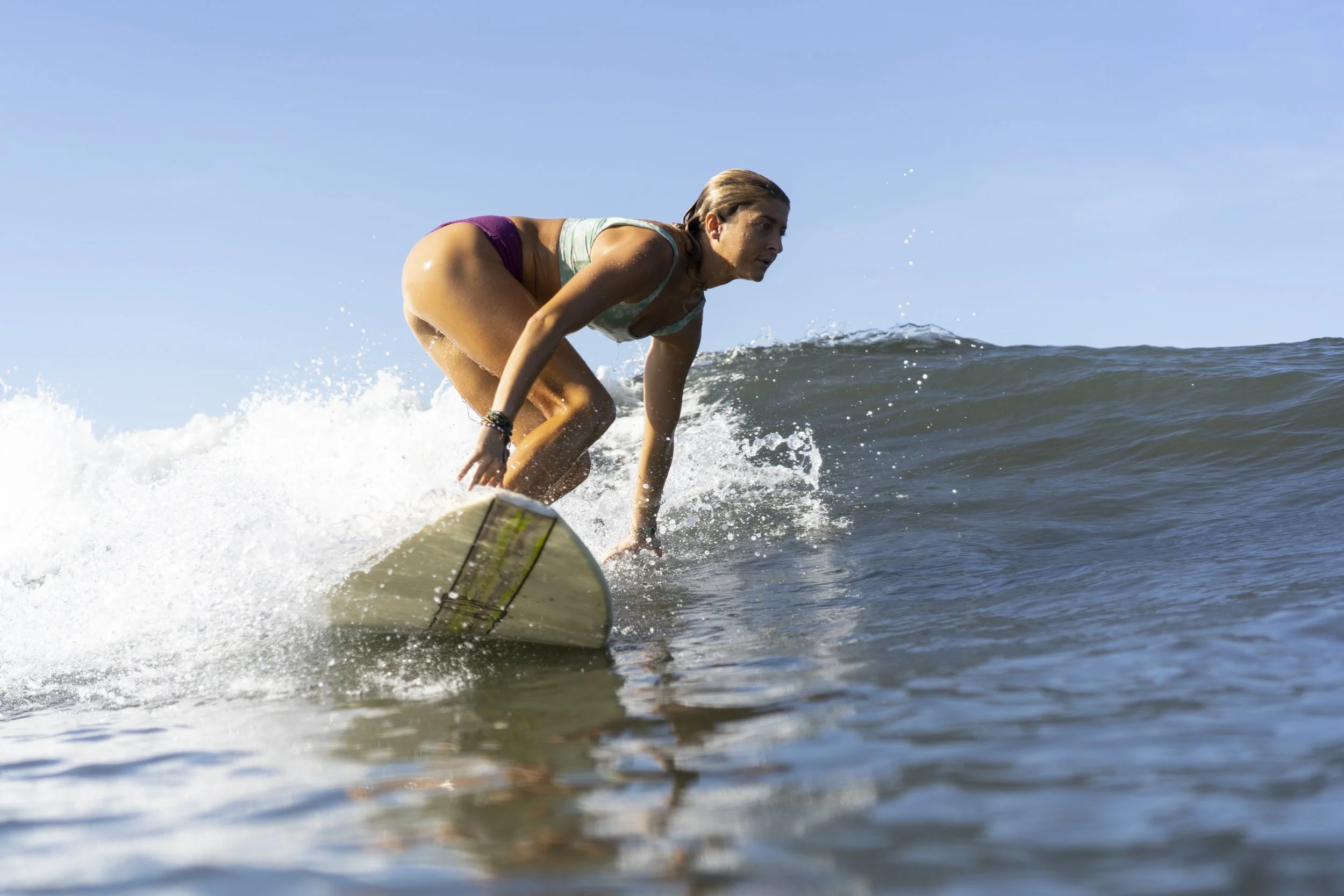Woman riding a clean blue wave on a longboard at a surf camp in Nicaragua