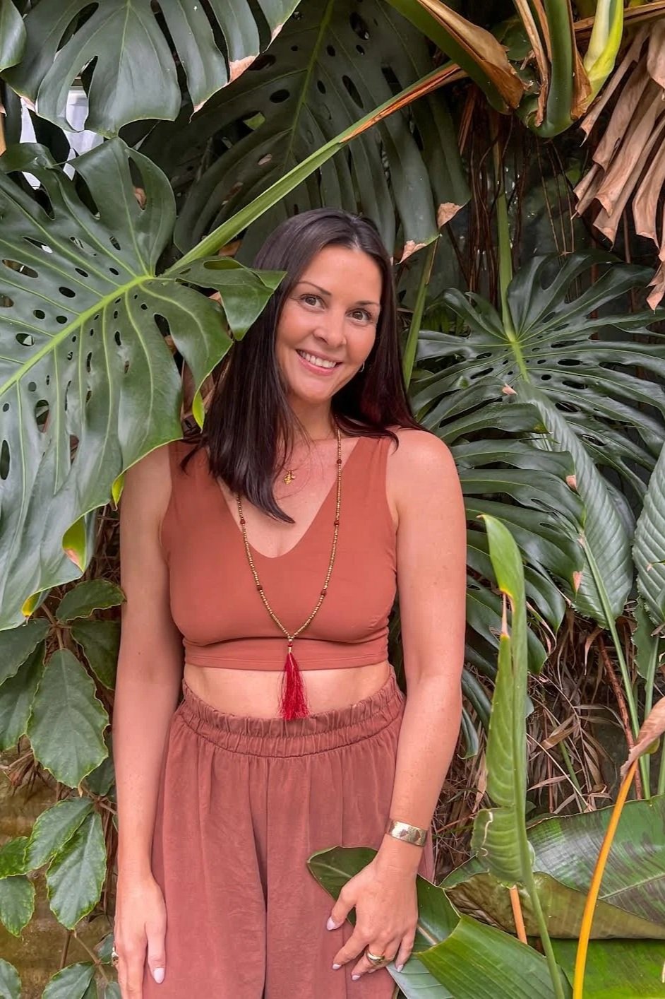 Jacqueline, yoga teacher, smiling among tropical jungle leaves ahead of the EVOLVE yoga teacher immersion in Nicaragua
