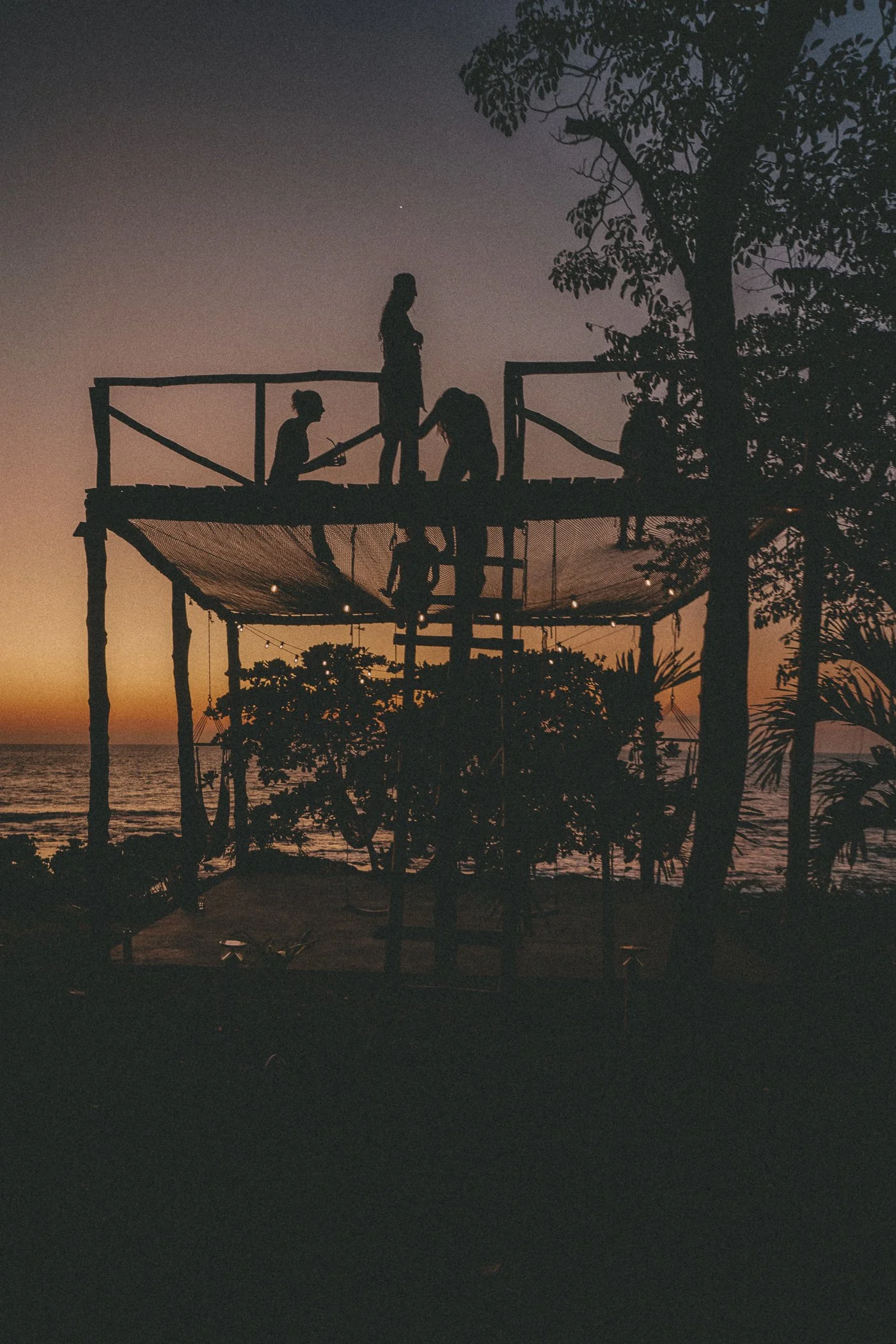 Silhouette of the two-story oceanfront hammock deck at dusk with guests watching the sunset at Still Salty Escape Nicaragua