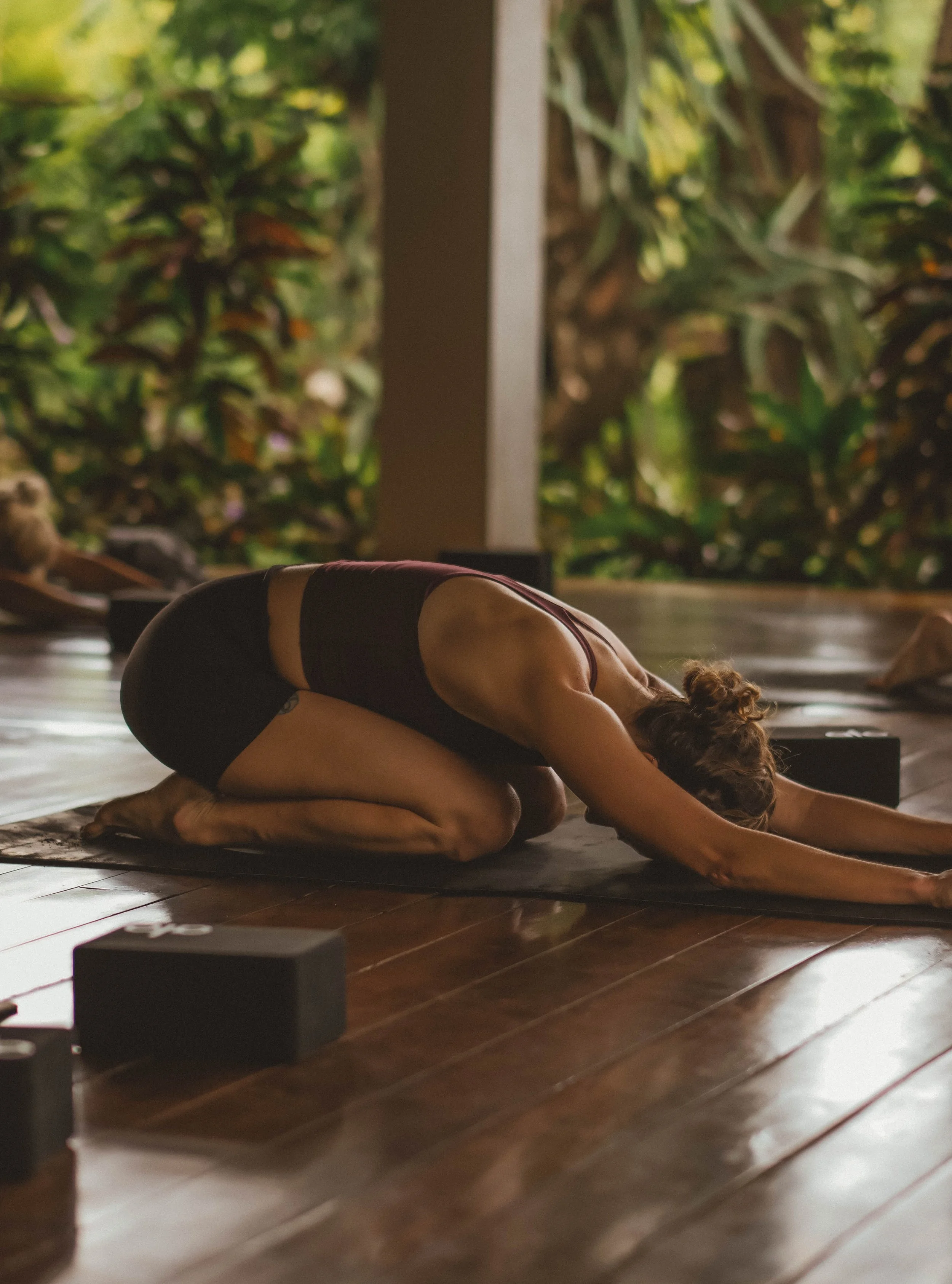 Group of yoga retreat guests resting in child's pose inside an open-air oceanfront shala in Nicaragua