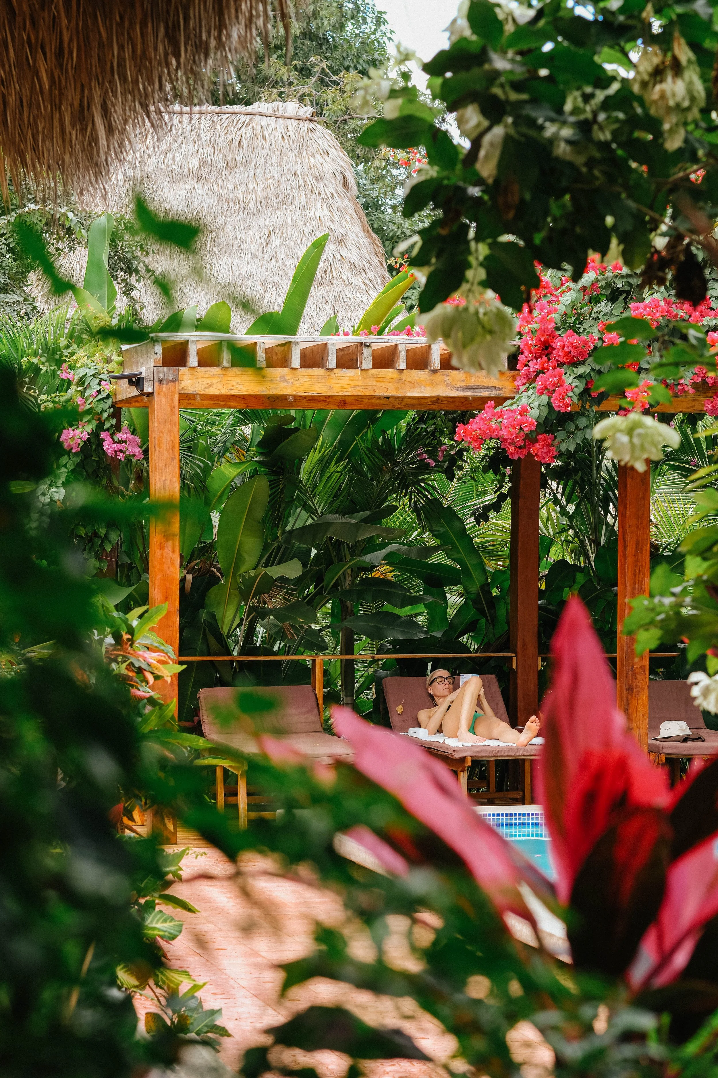 Woman relaxing on a lounge chair reading during downtime by a tropical pool at a yoga retreat in Nicaragua