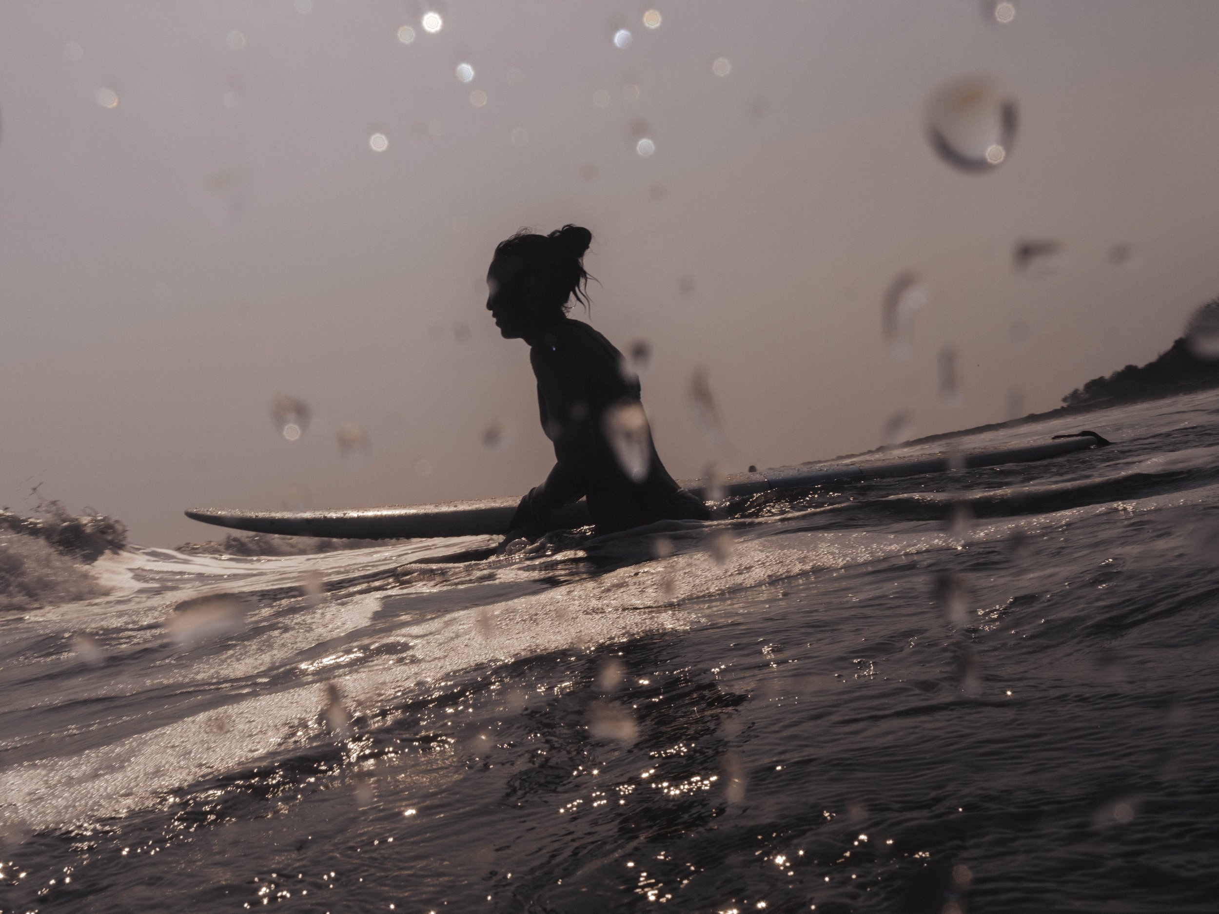 Surfer sitting on a longboard at sunset during a surf retreat on Nicaragua's northern Pacific coast