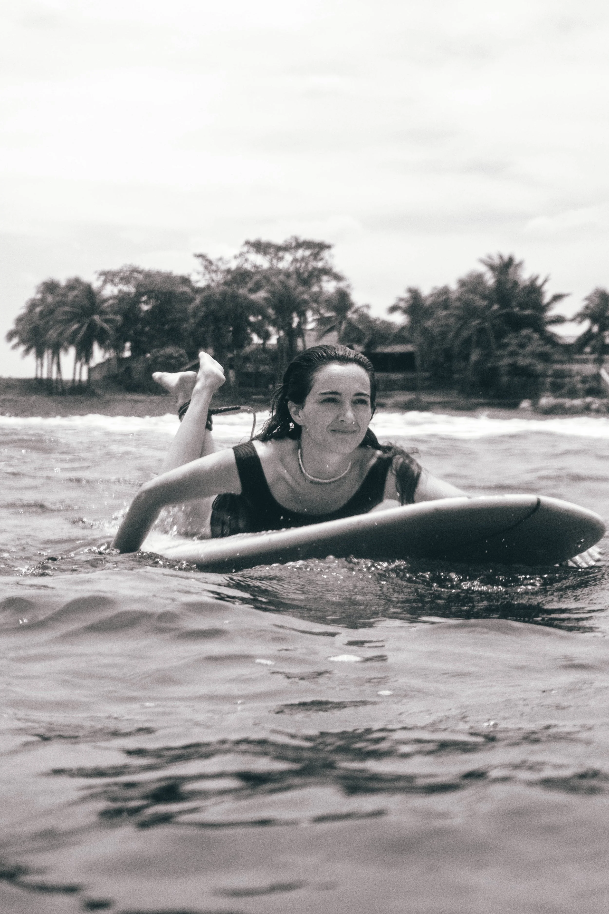 black and white photo of a woman paddling out on her surfboard at a surf retreat in Nicaragua