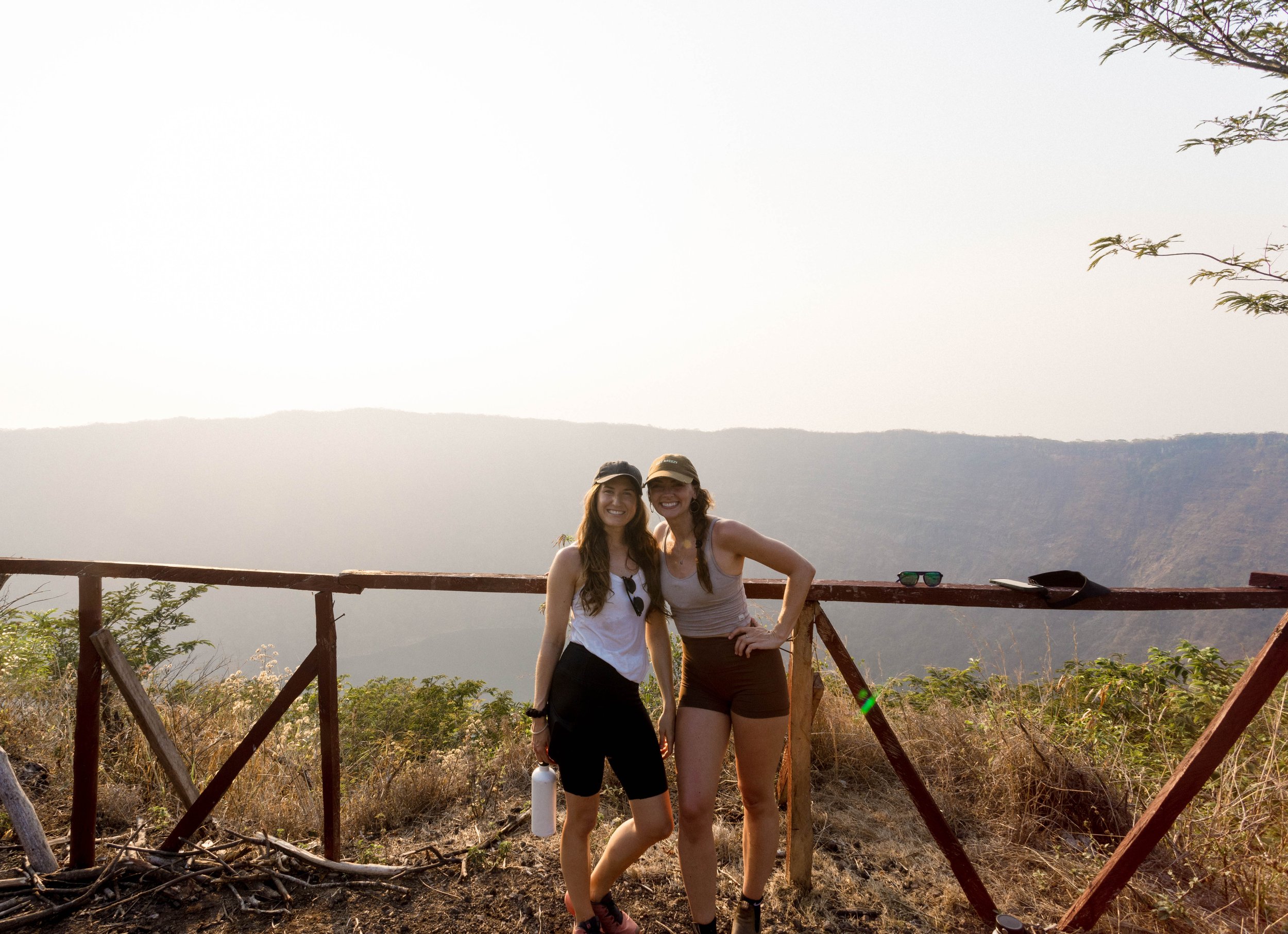 Two women travelers smiling in front of a volcano in Nicaragua during a safe surf trip