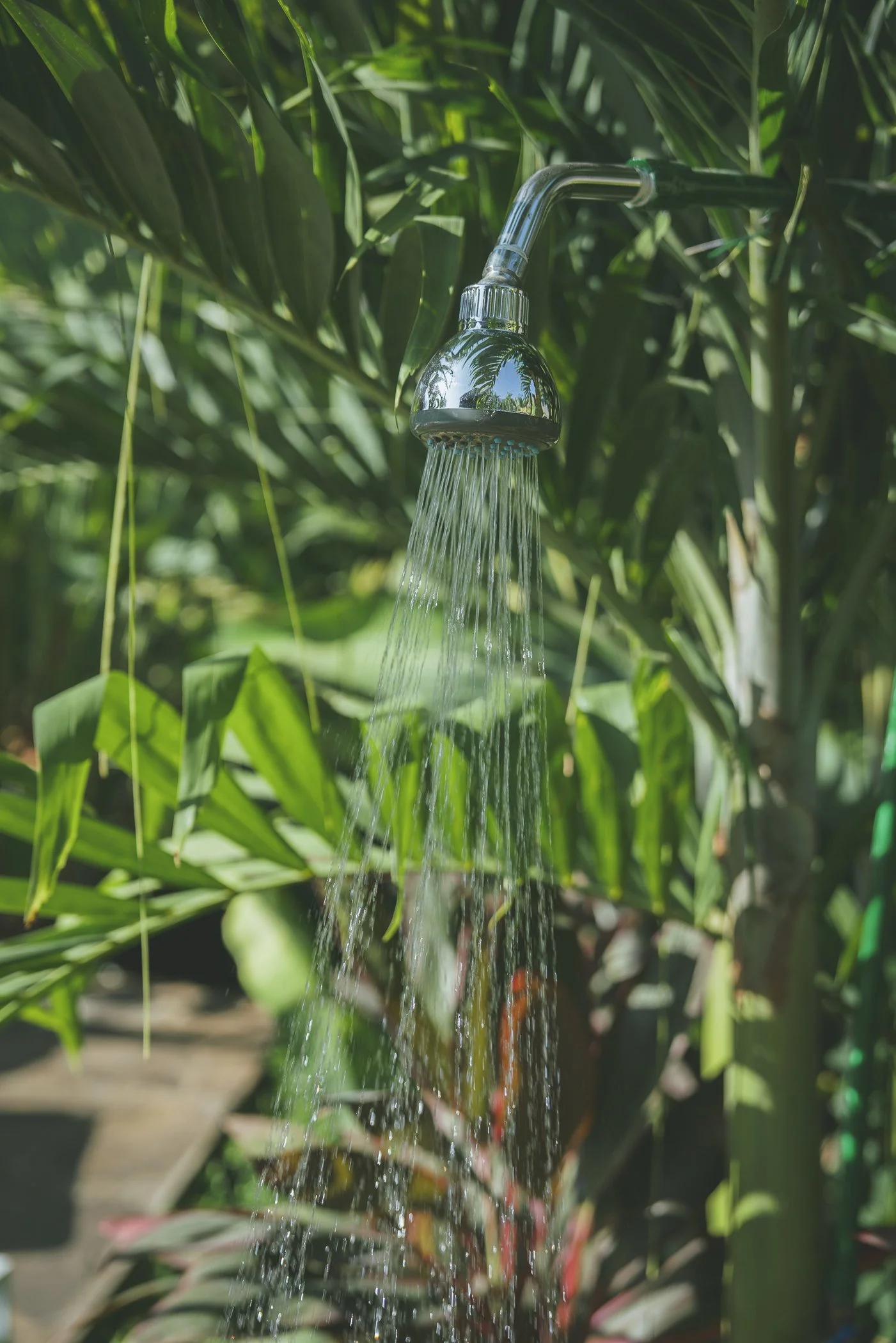 Chrome outdoor shower running amid lush tropical greenery at a surf and yoga retreat venue in Nicaragua