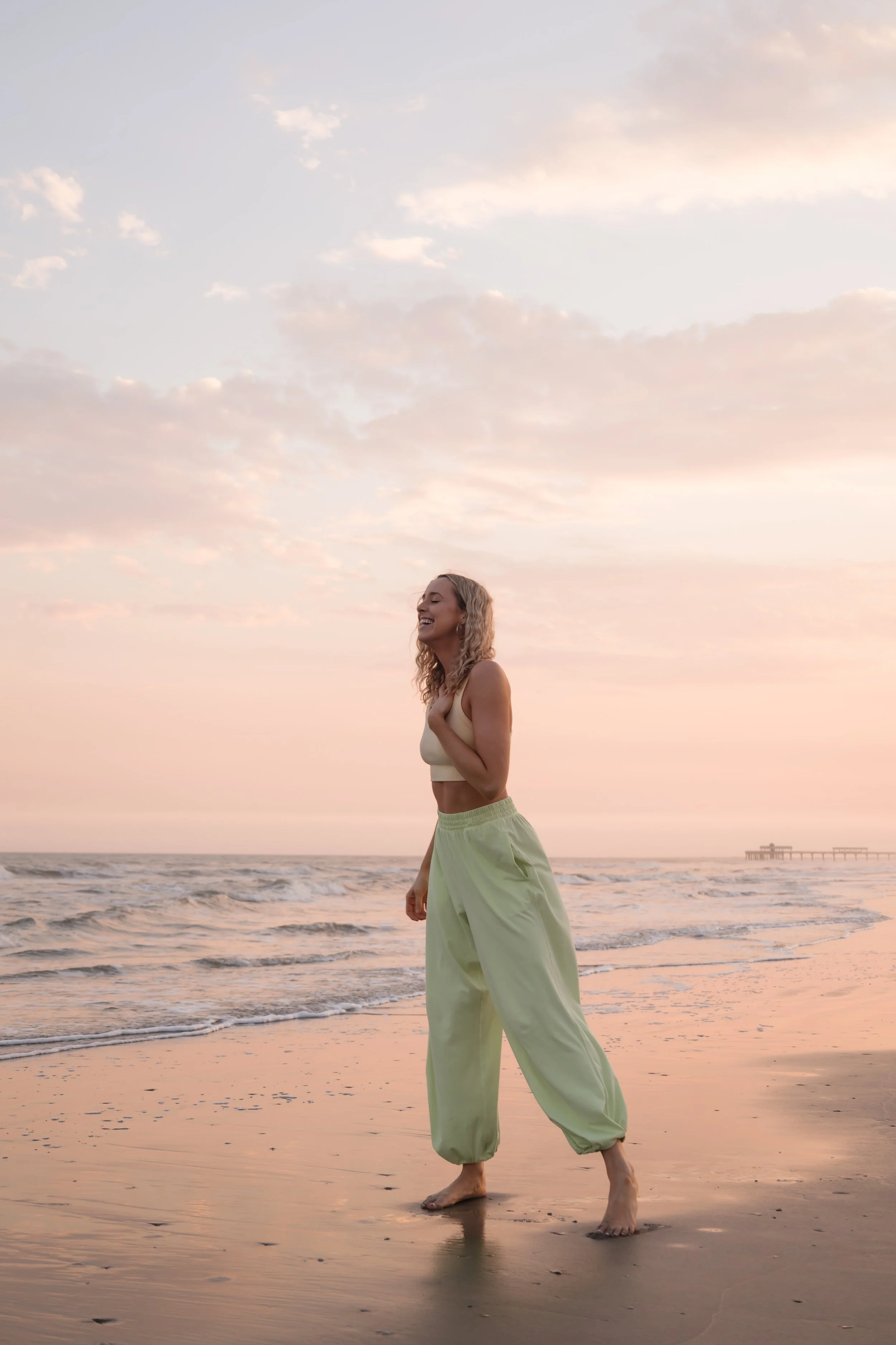 Taylor Kornegay, yoga teacher and breathwork facilitator leading the Heartspace retreat in Nicaragua, laughing barefoot on the beach at sunset