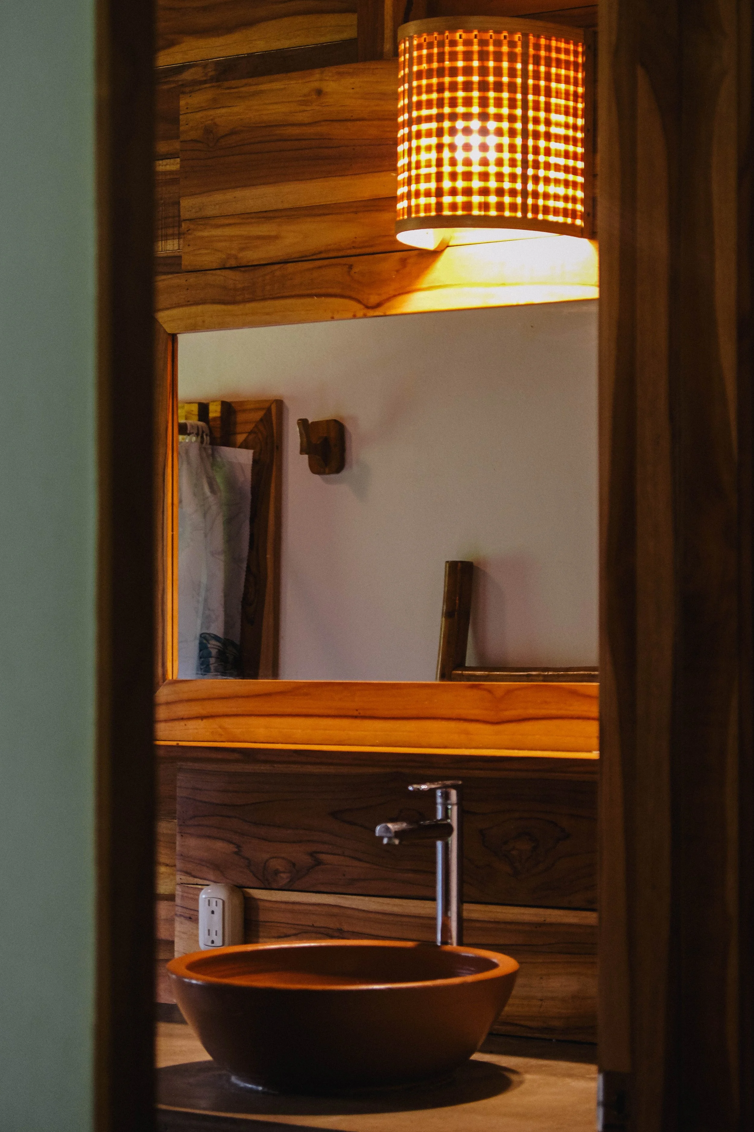 Sleek indoor ensuite bathroom with a clay bowl sink and teak vanity in an upstairs cabaña at a Nicaragua surf and yoga retreat