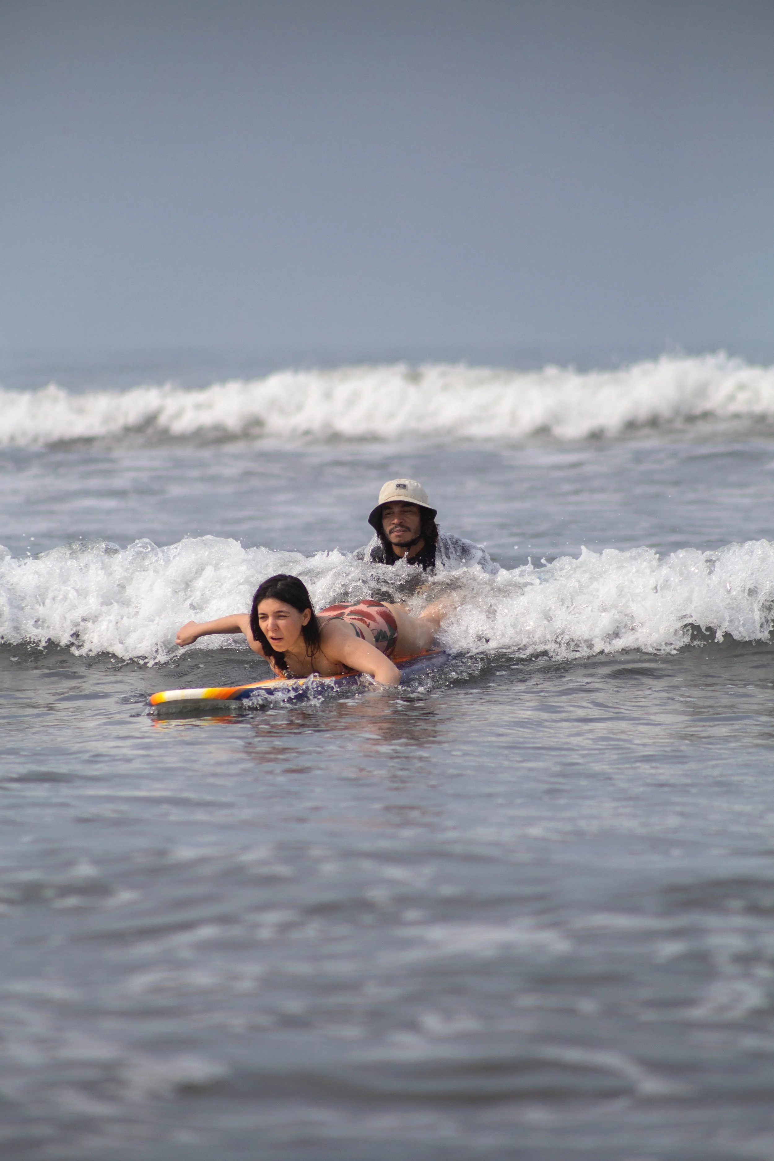 Instructor pushing a beginner into a wave during a learn to surf lesson at a Nicaragua surf camp