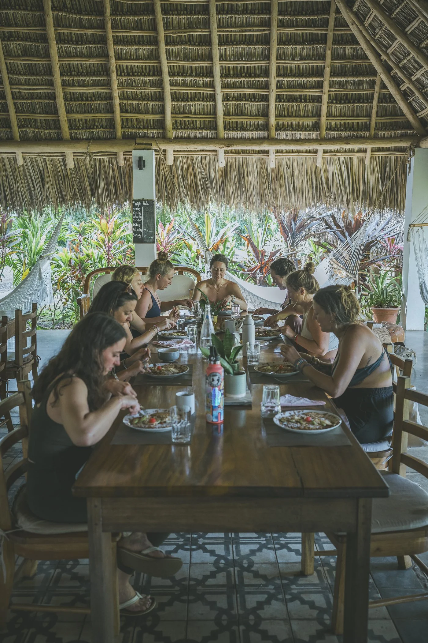 Group of women sharing a meal together at the long open-air community table under the thatched palapa at Still Salty Escape Nicaragua