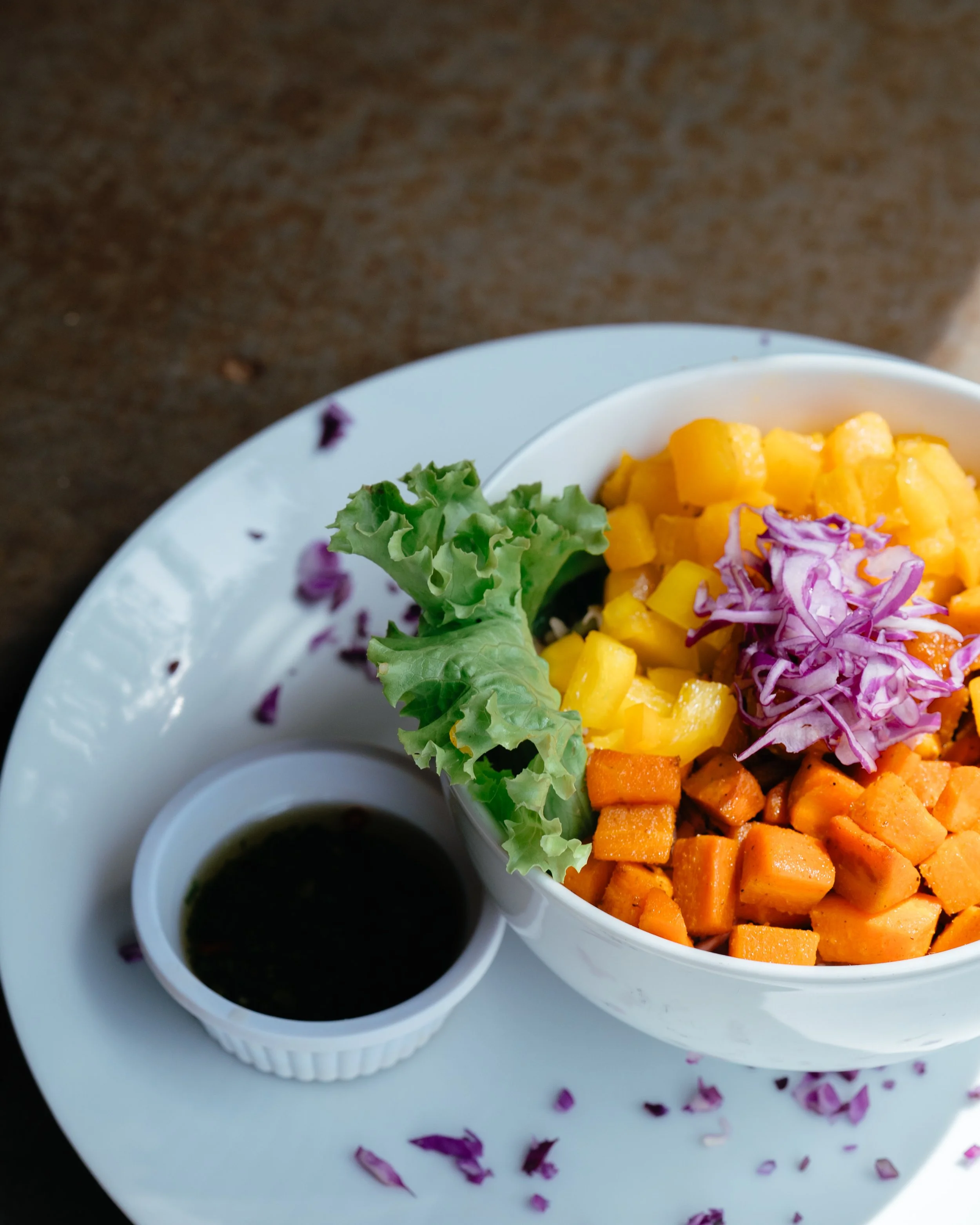 Whole-food bowl with roasted sweet potato, mango, and cabbage with a side of dressing at a farm-to-table retreat in Nicaragua