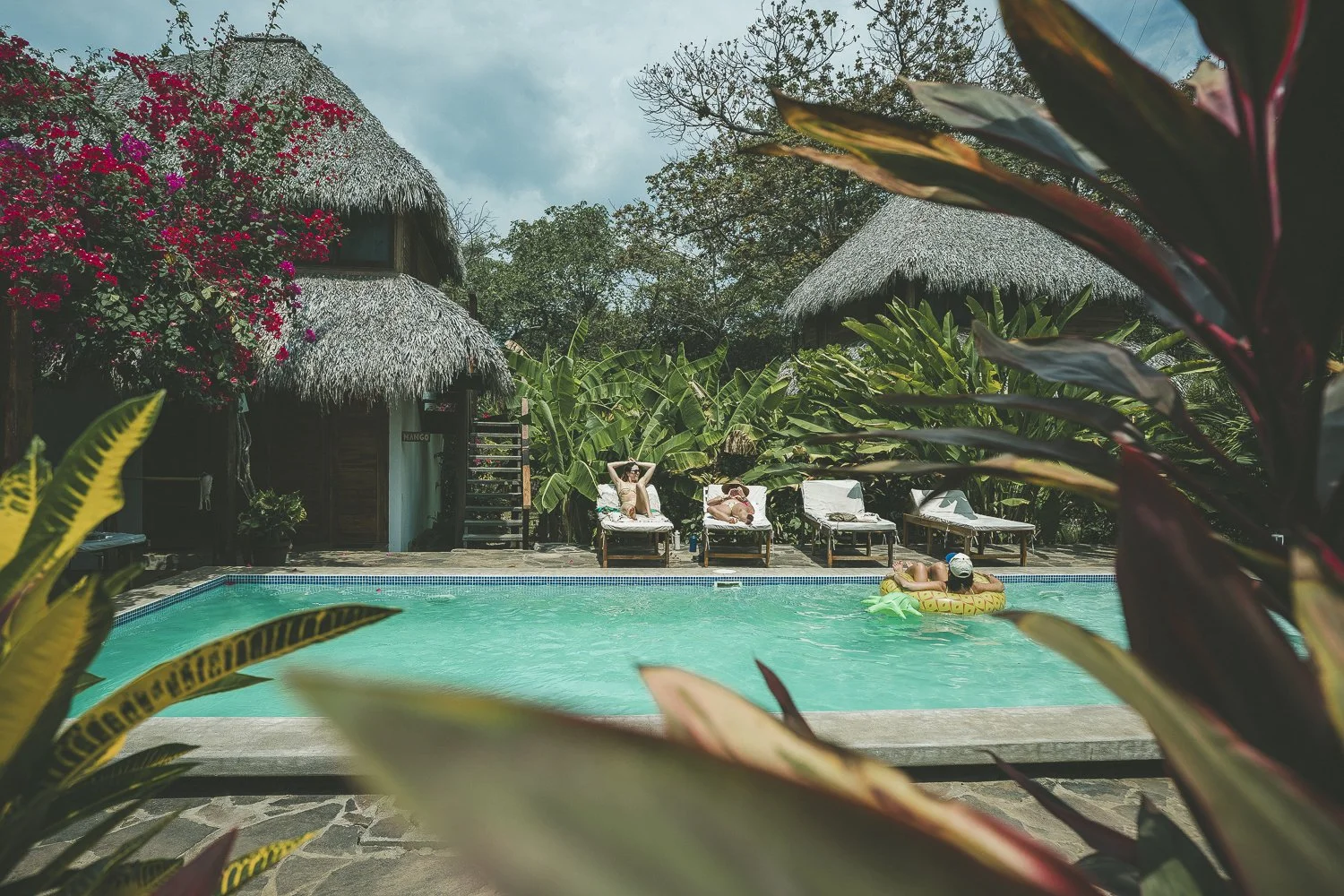 Guests lounging and floating in the private pool beside thatched cabañas at Still Salty Escape retreat venue in Nicaragua