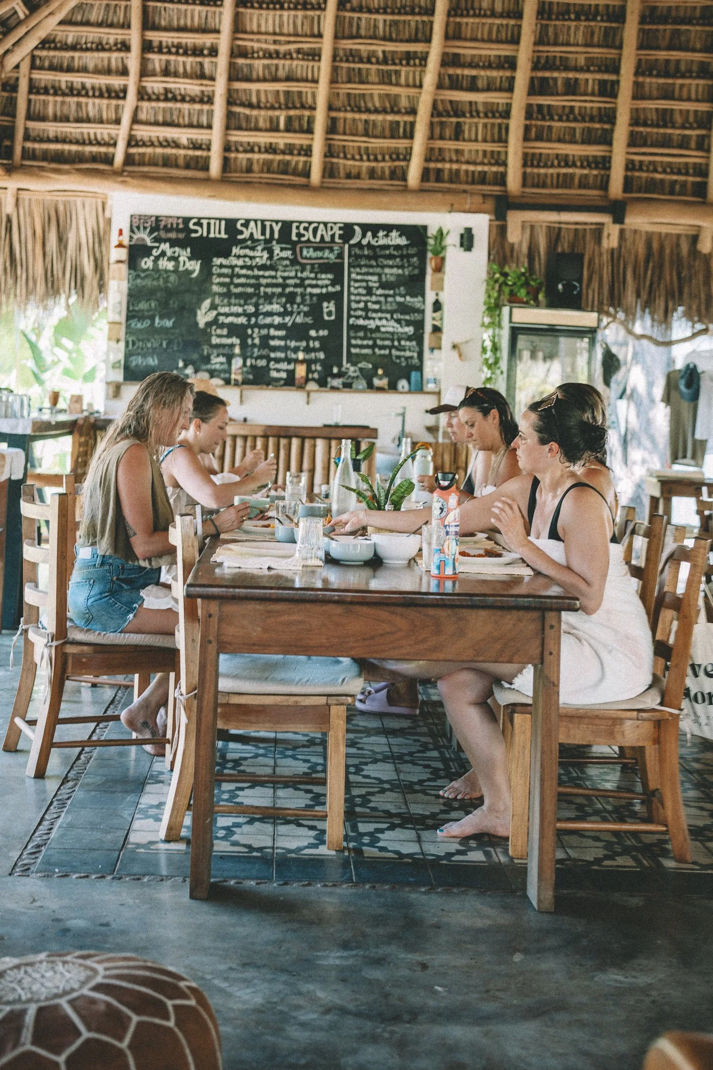 Retreat group sharing a meal at the open-air community table under the thatched palapa at Still Salty Escape Nicaragua