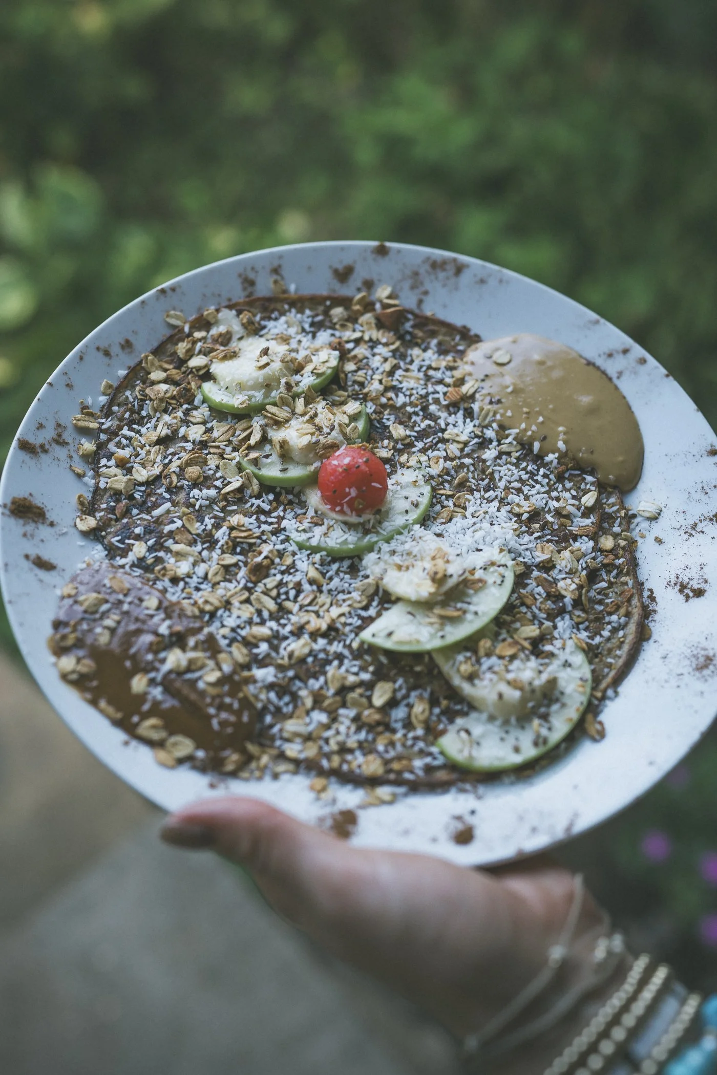 Gluten-free sugar-free pancake topped with granola, coconut, apple, banana, and nut butter made with farm ingredients at Still Salty Escape in Nicaragua